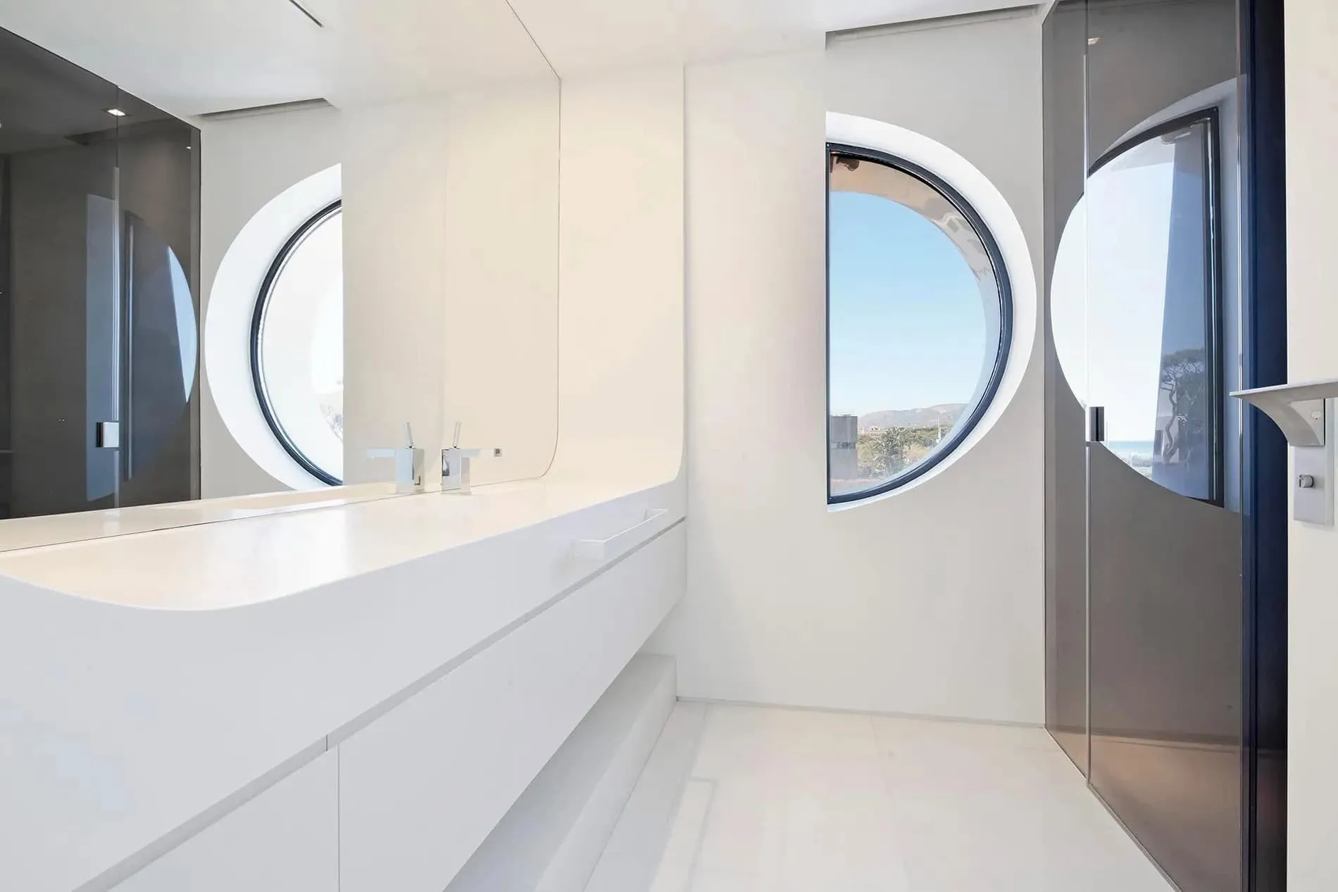 白色雕塑式房间，配有大弯曲窗户和海景