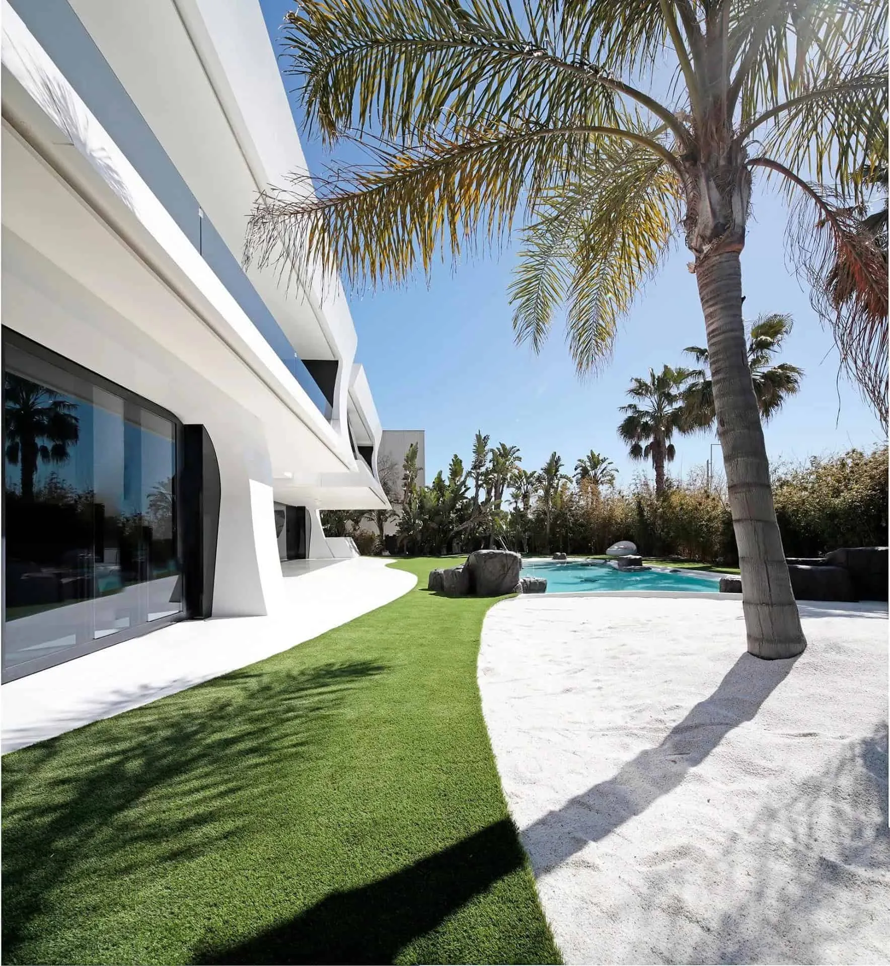 白色几何别墅侧面视图，周围环绕热带植被