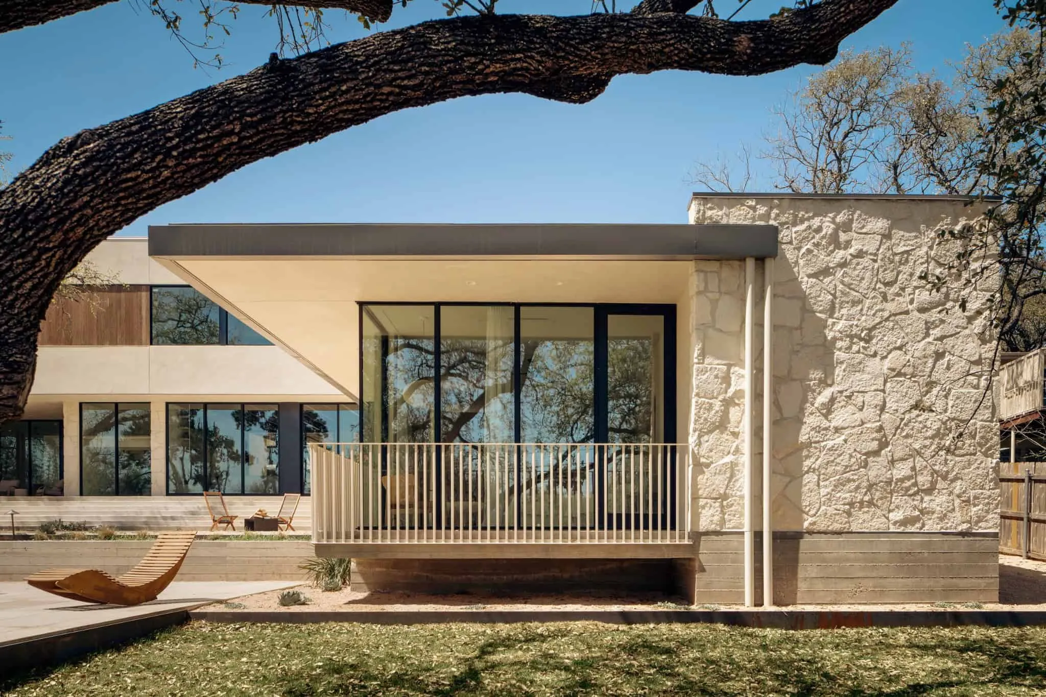 Боковой вид на Casa Solis с текстурированной каменной стеной и большими стеклянными панелями.