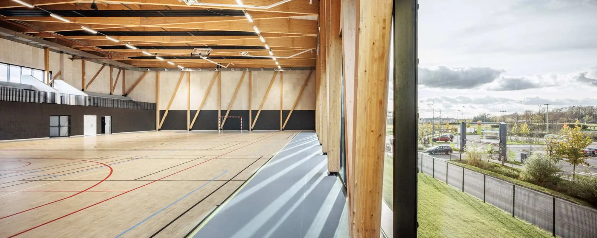 Interior of the Mennese Sports Hall with visible wooden beams and marked courts.