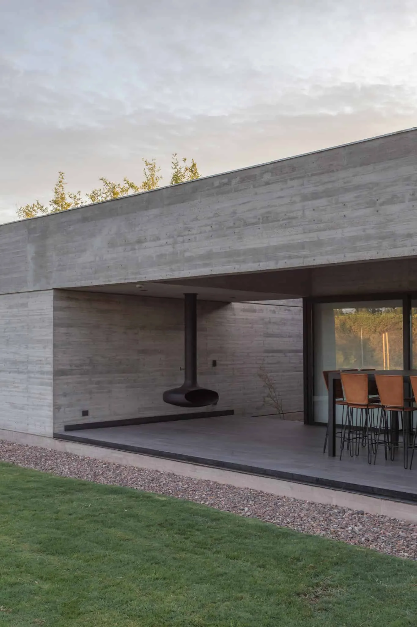 A4estudio设计的Casa Anabela混凝土墙上的悬挂黑色壁炉。