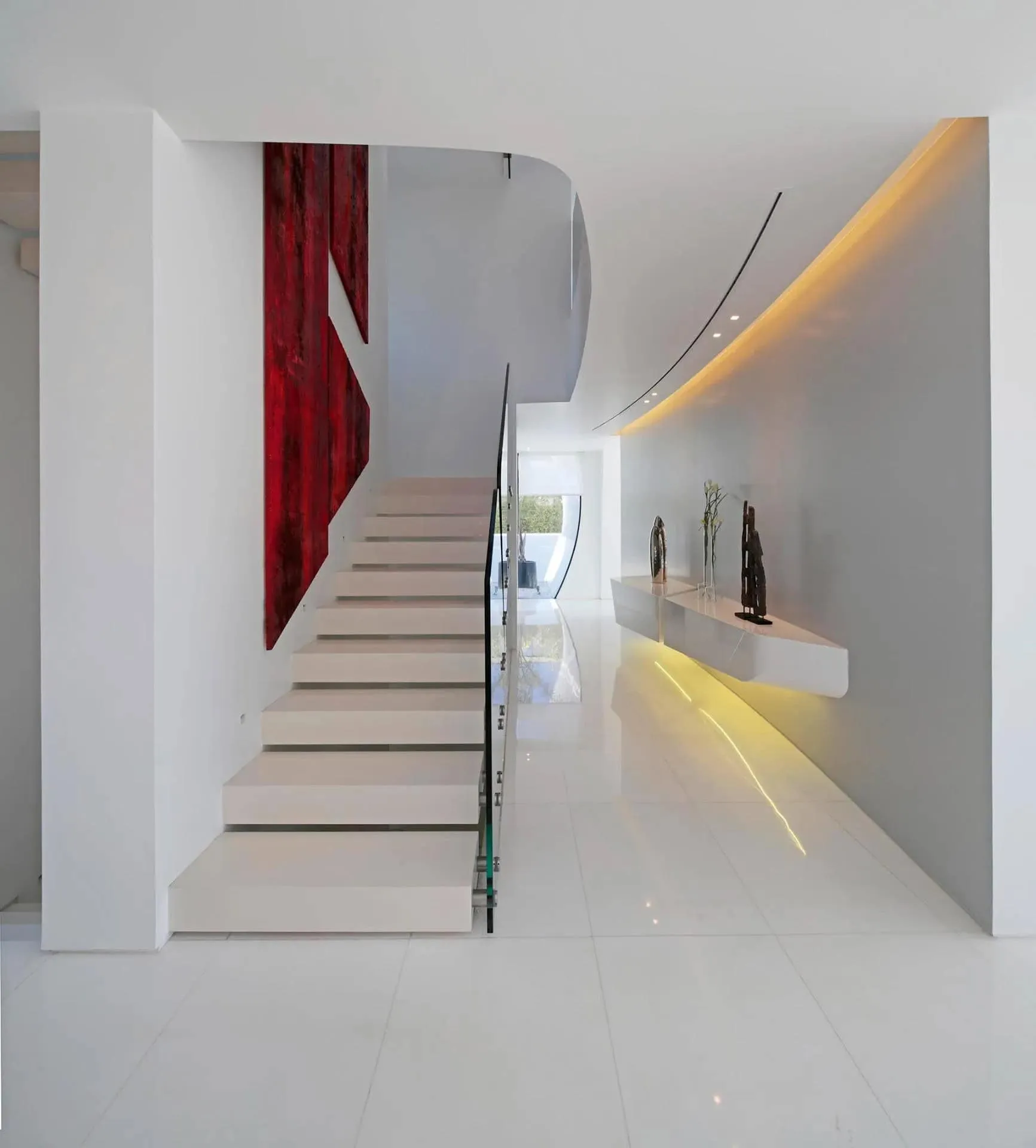 白色漂浮楼梯，配有玻璃扶手和弯曲天花板，展示明亮极简内饰