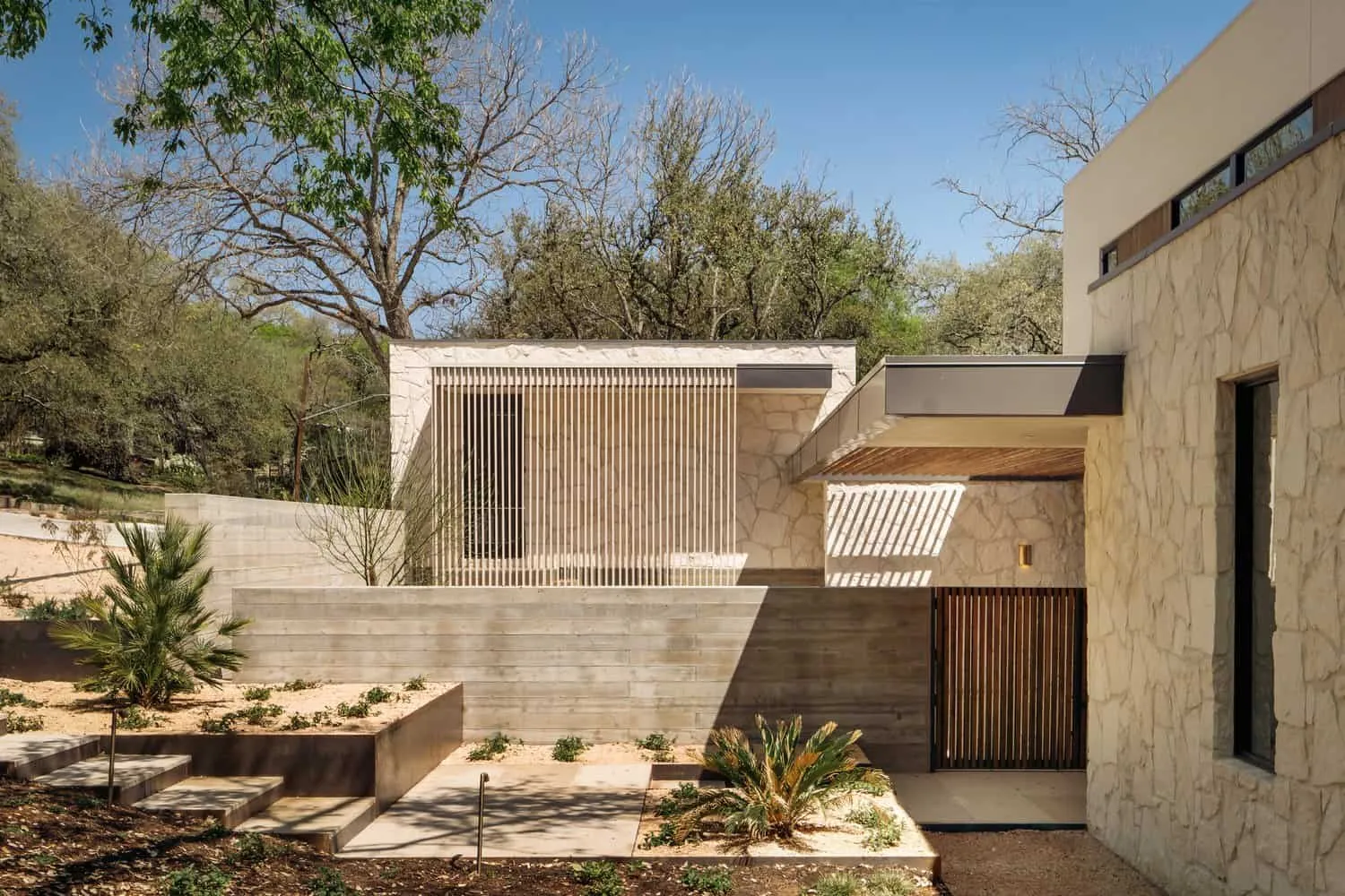 Гостиная Casa Solis с каменной стеной, встроенными полками и современным камино.