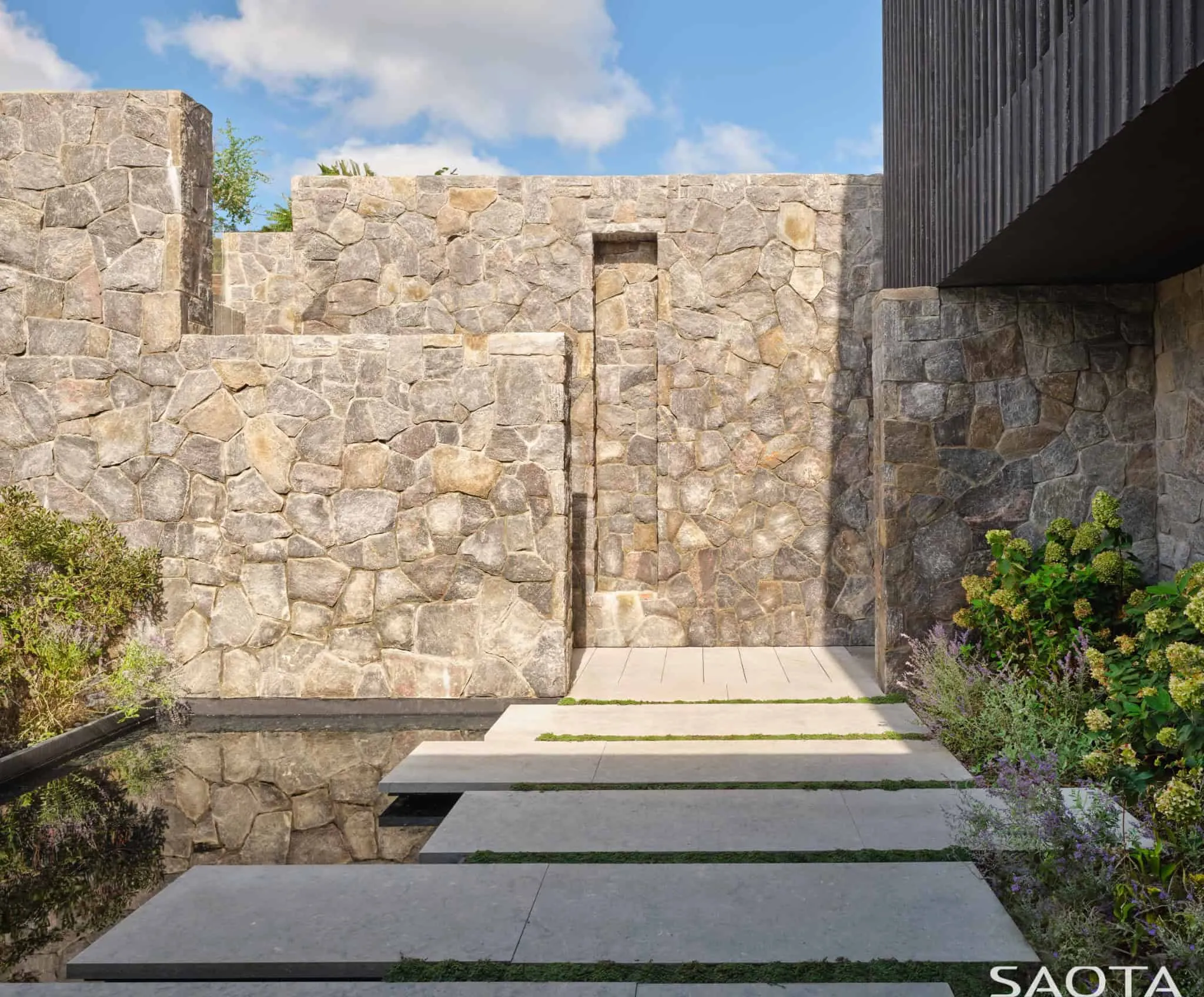 带有石墙和本地植物的蒙托克住宅入口小径。