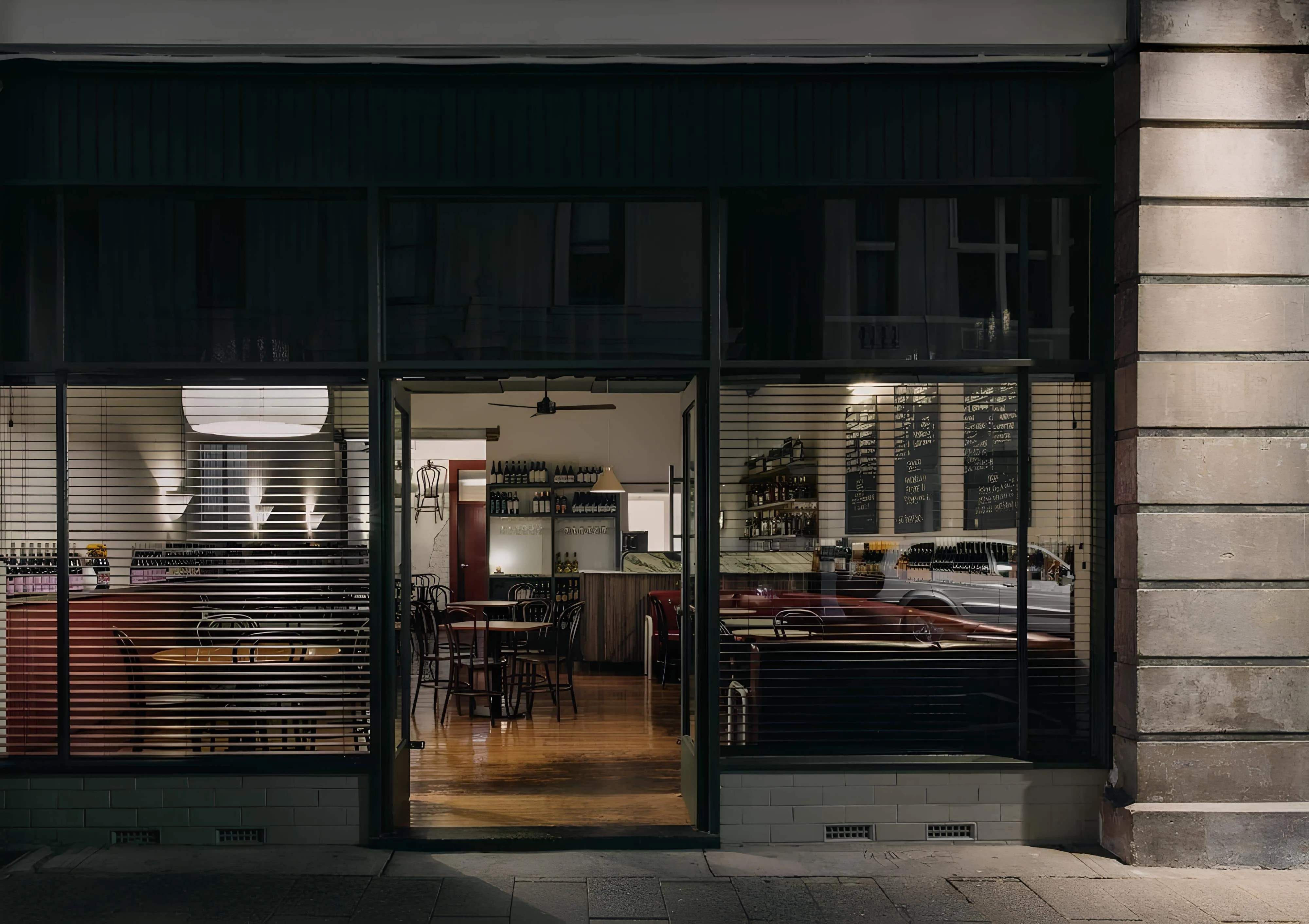 Exterior view of Vin Populi Next Door in Fremantle with warm atmospheric lighting through glass facade