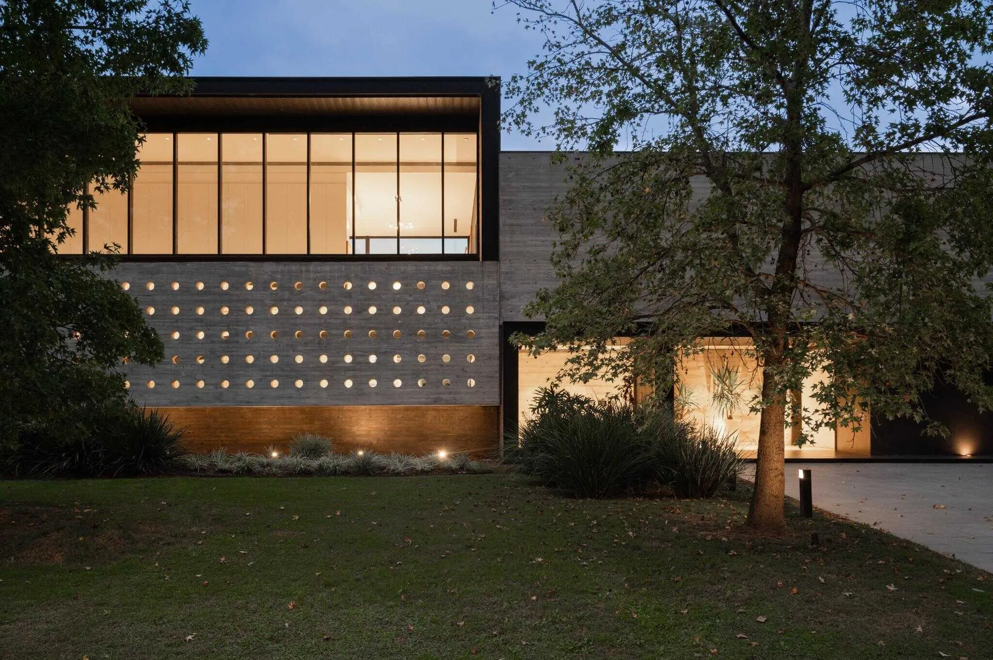帕切科住宅夜间外观，展示温暖内部照明和规律的孔洞节奏