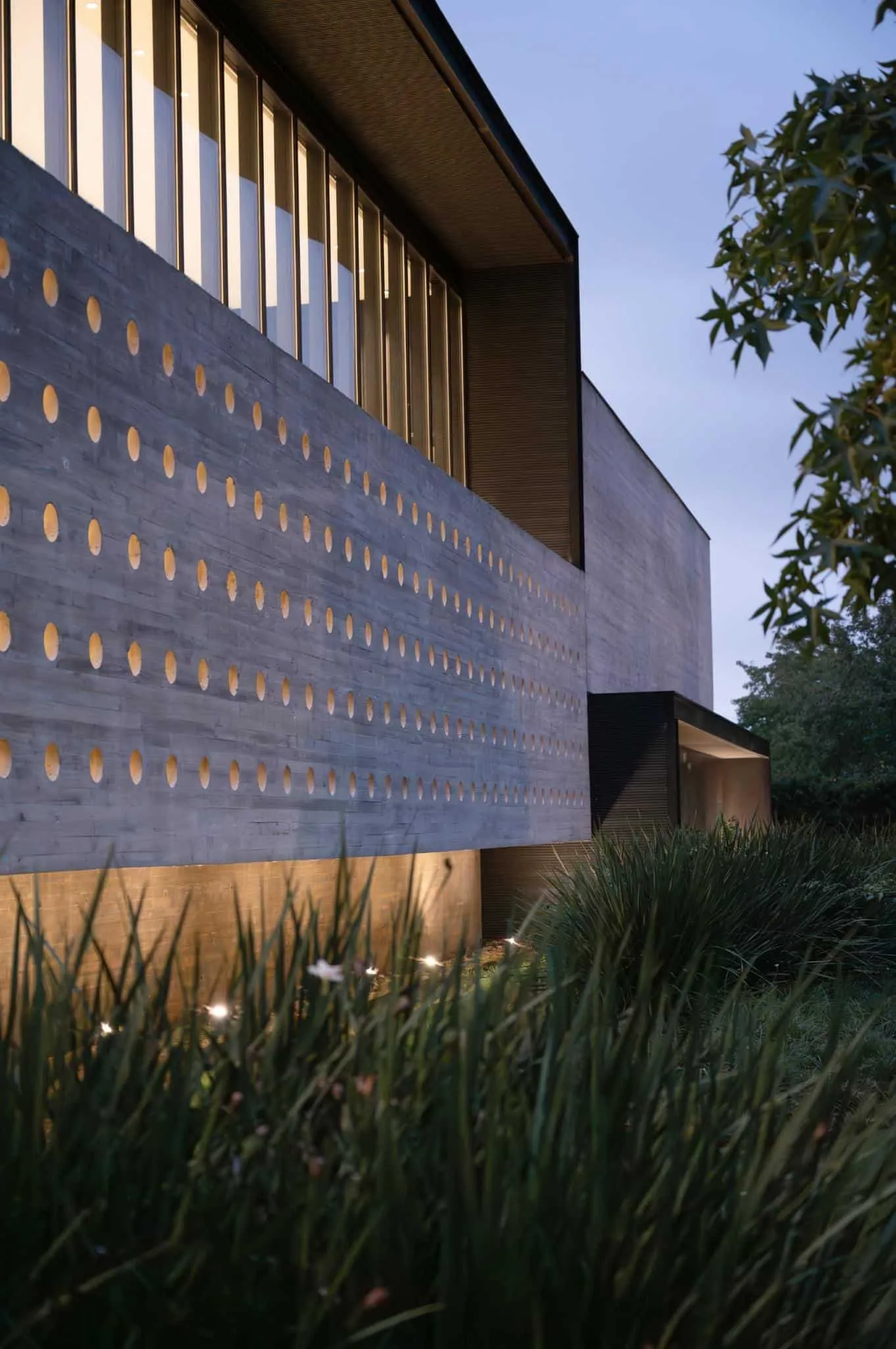 帕切科住宅穿孔立面在日落时的温暖灯光