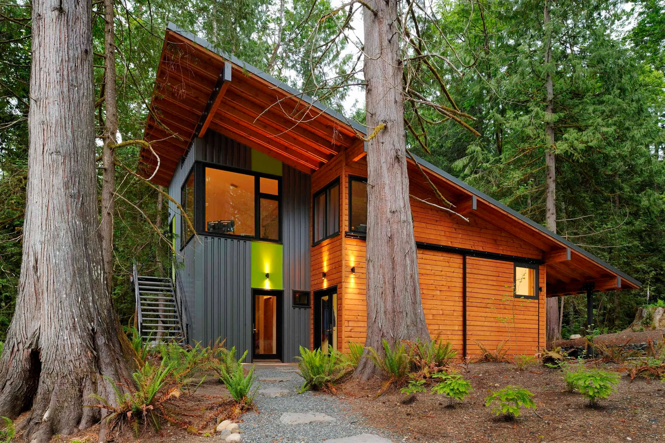 Modern forest cabin with wooden and metal facade, large windows and shed roof