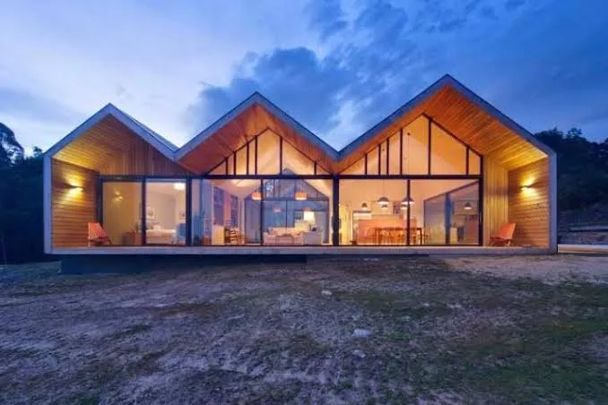 Modern house with an M-shape roof, floor-to-ceiling glass facade and wooden finish