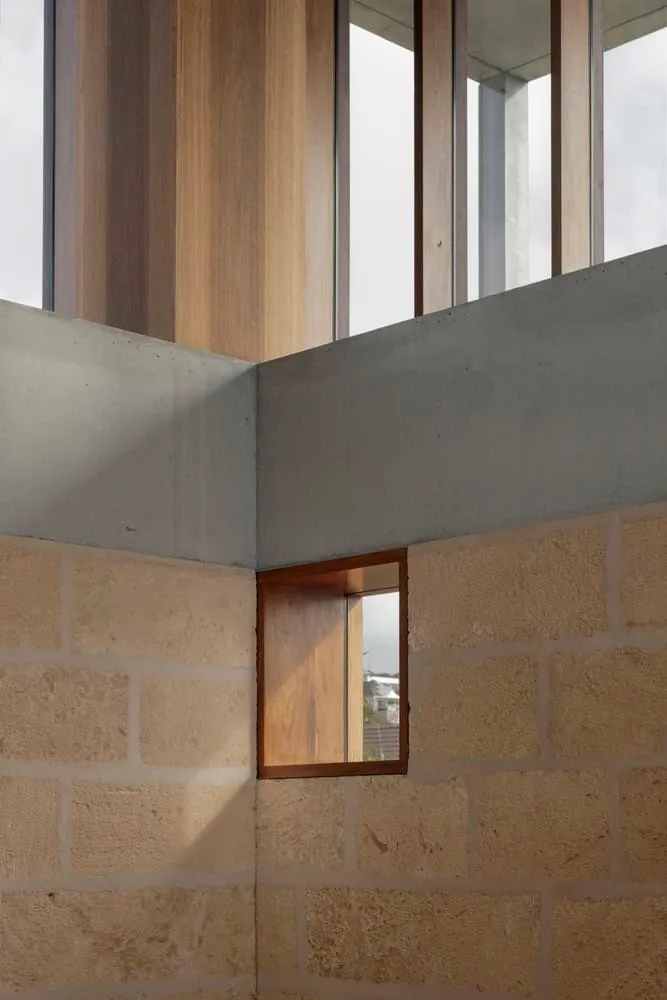 Intersection of limestone wall and wooden structure with square window in Newcastle