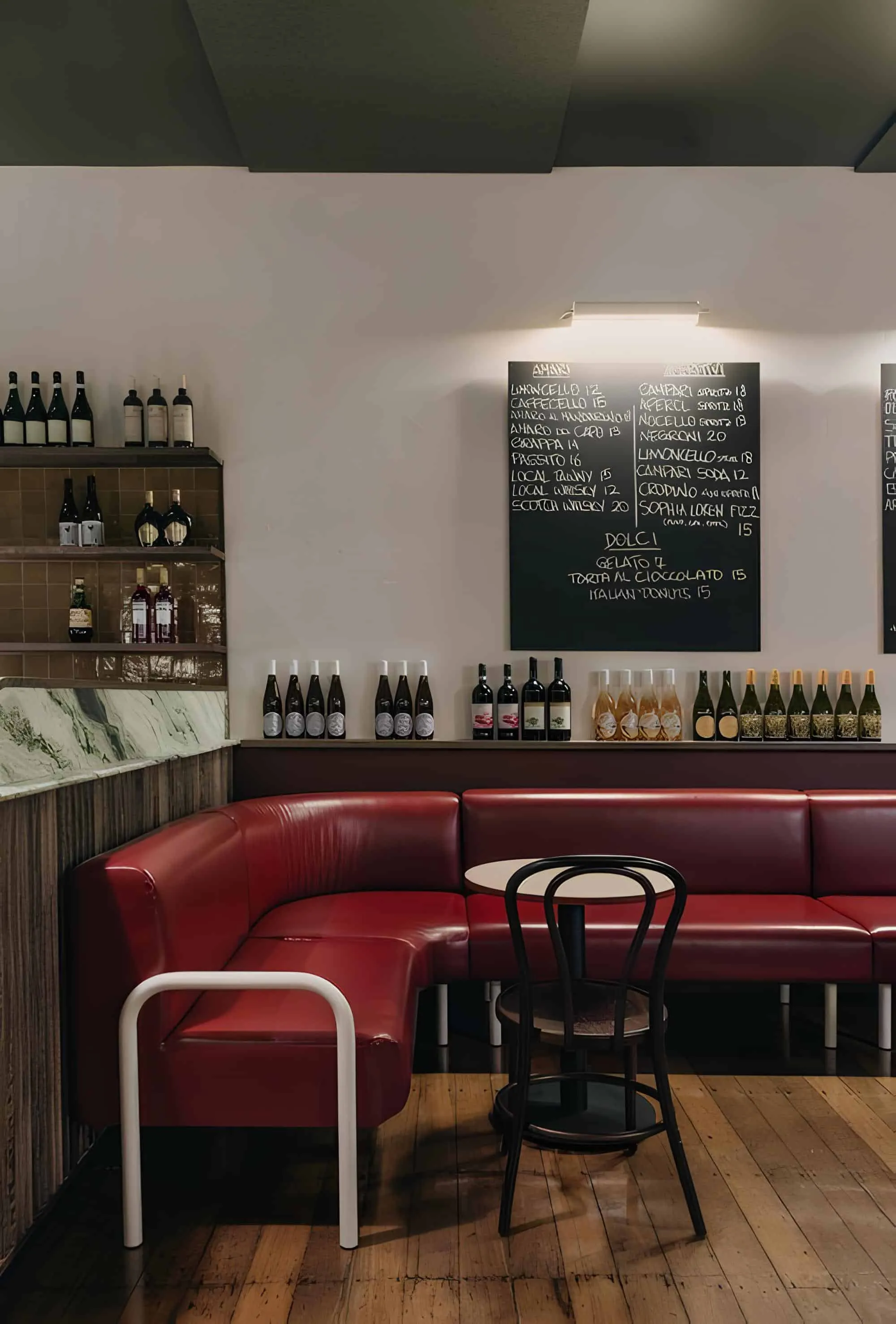 Bar corner with red L-shaped leather stool and wine board