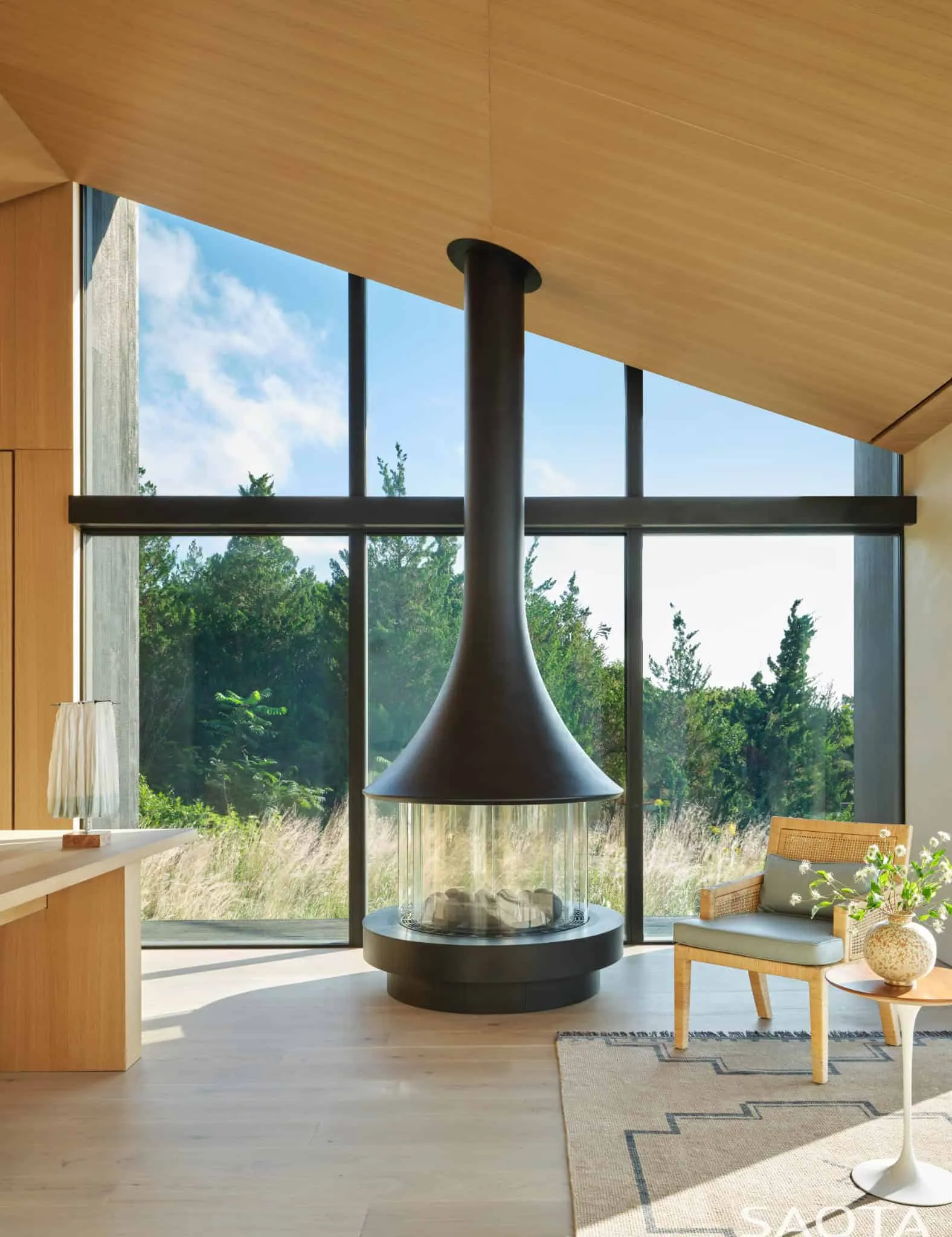 蒙托克住宅的现代壁炉和面向森林的大窗户休闲椅