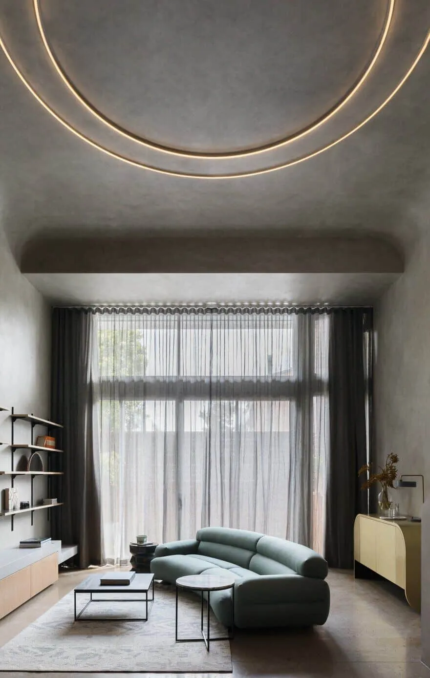 Living area with arched ceiling and circular LED lighting in a brutalist apartment