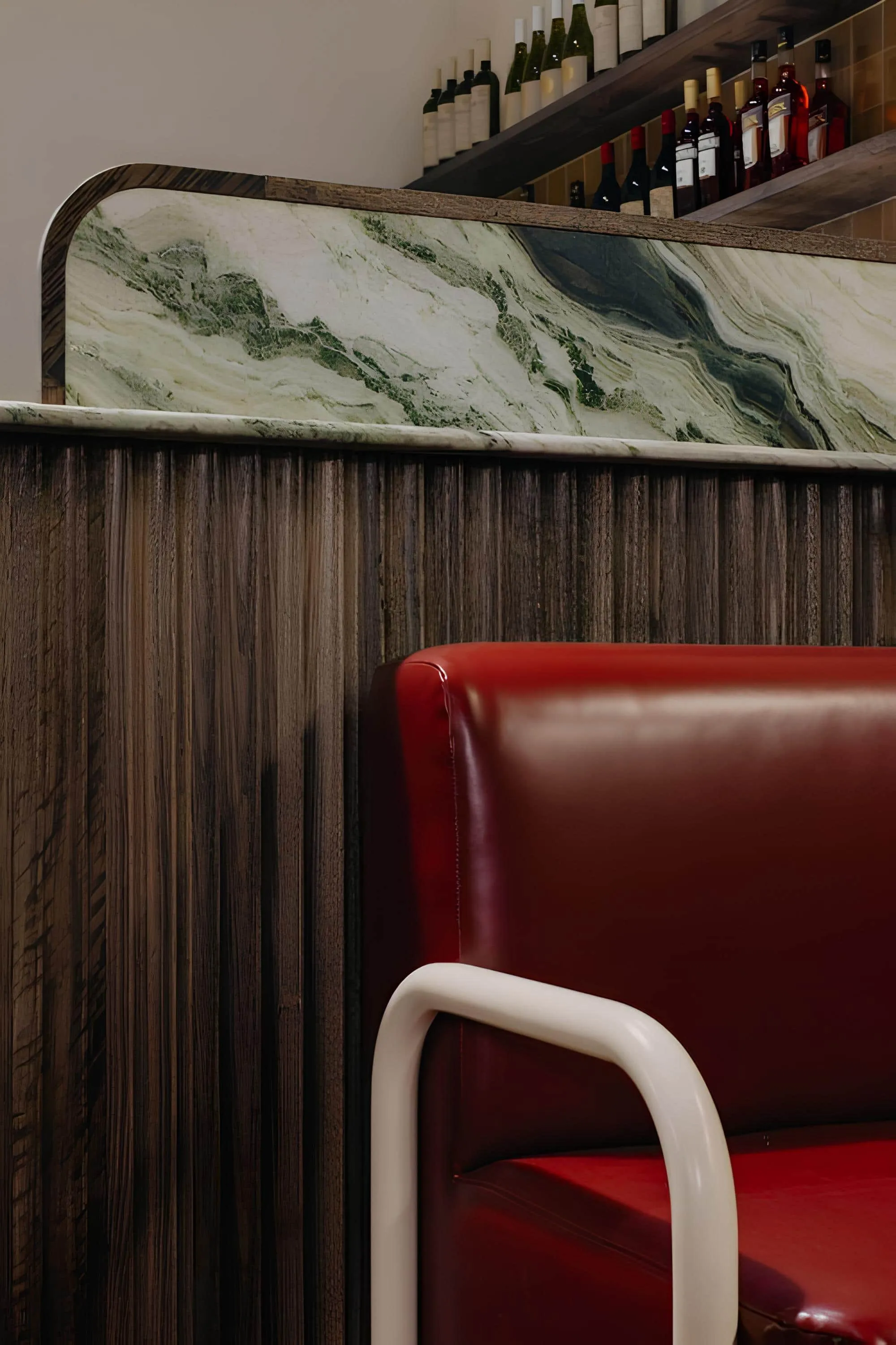 Close-up of greenish marble above fibrous wooden panel and red leather seat
