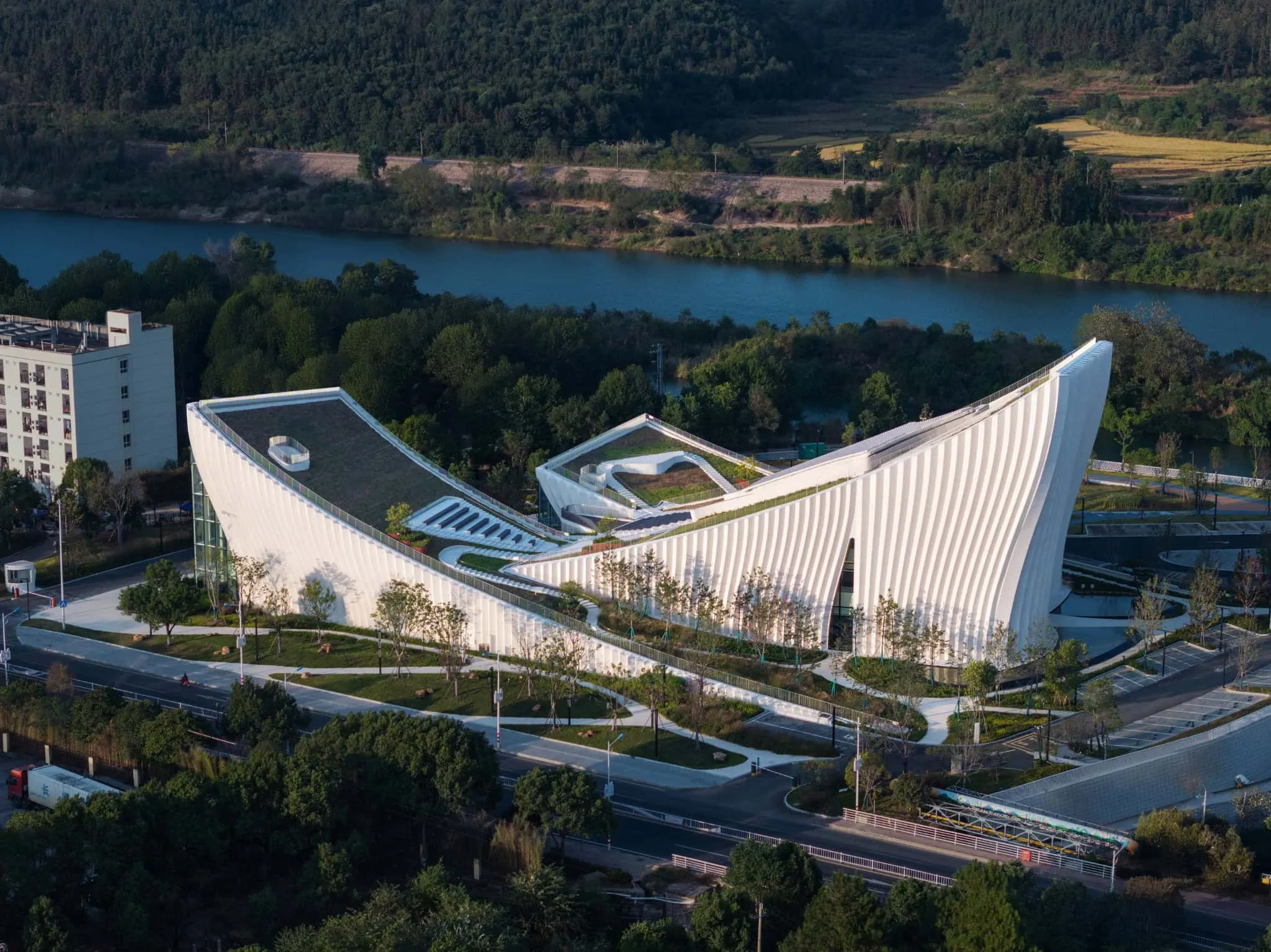 View of Sunner Museum facade with river Aerial view of Sunner Museum by river, showing elegant sloped roofs