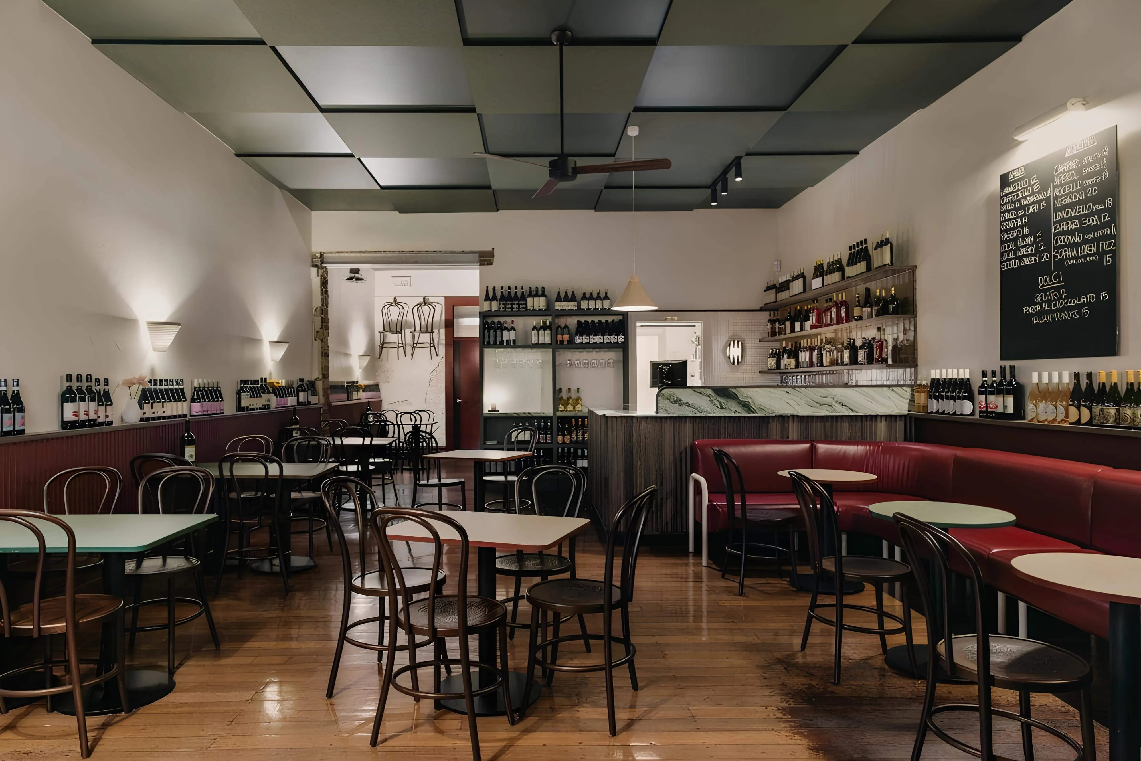 Interior of Vin Populi Next Door with red bar stools, green marble counter and wine-stocked walls