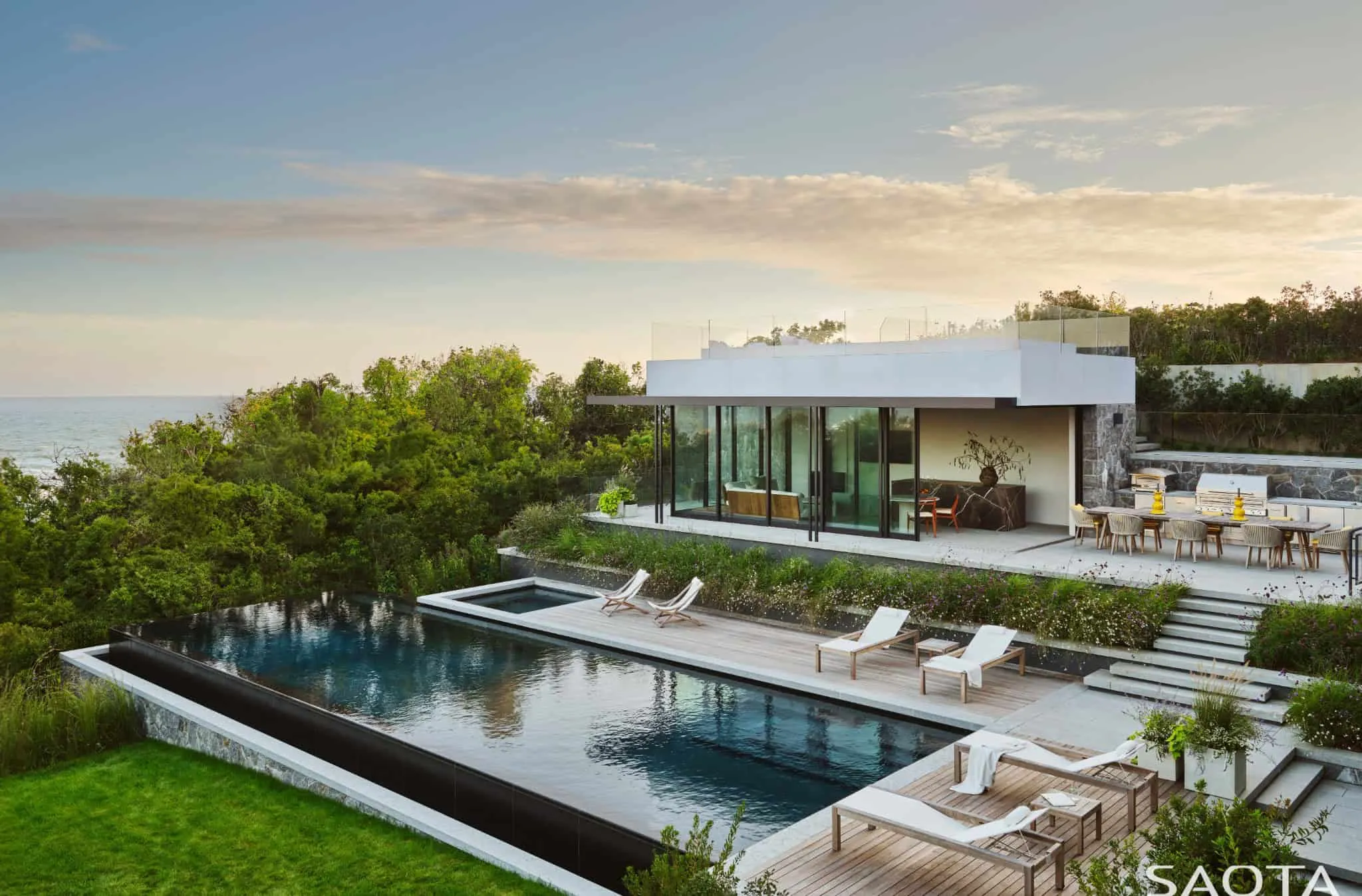 蒙托克住宅的无尽泳池和露台，配有躺椅，面向大海。