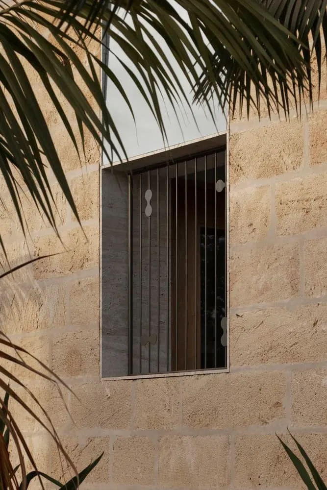 Textured stone facade with square window and artistic metal grilles in Newcastle