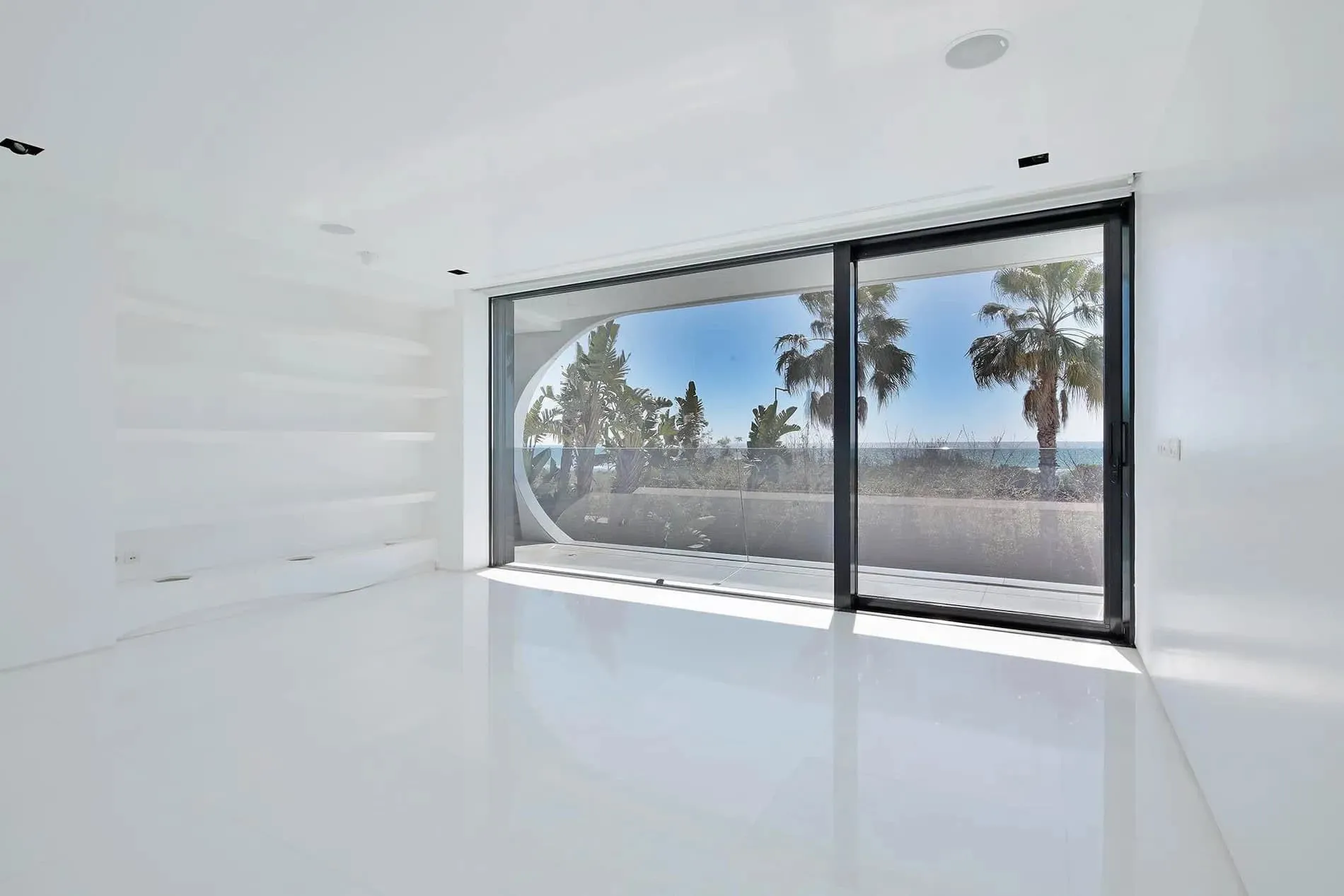 极简白色浴室，配有圆形窗户和雕塑式洗手盆