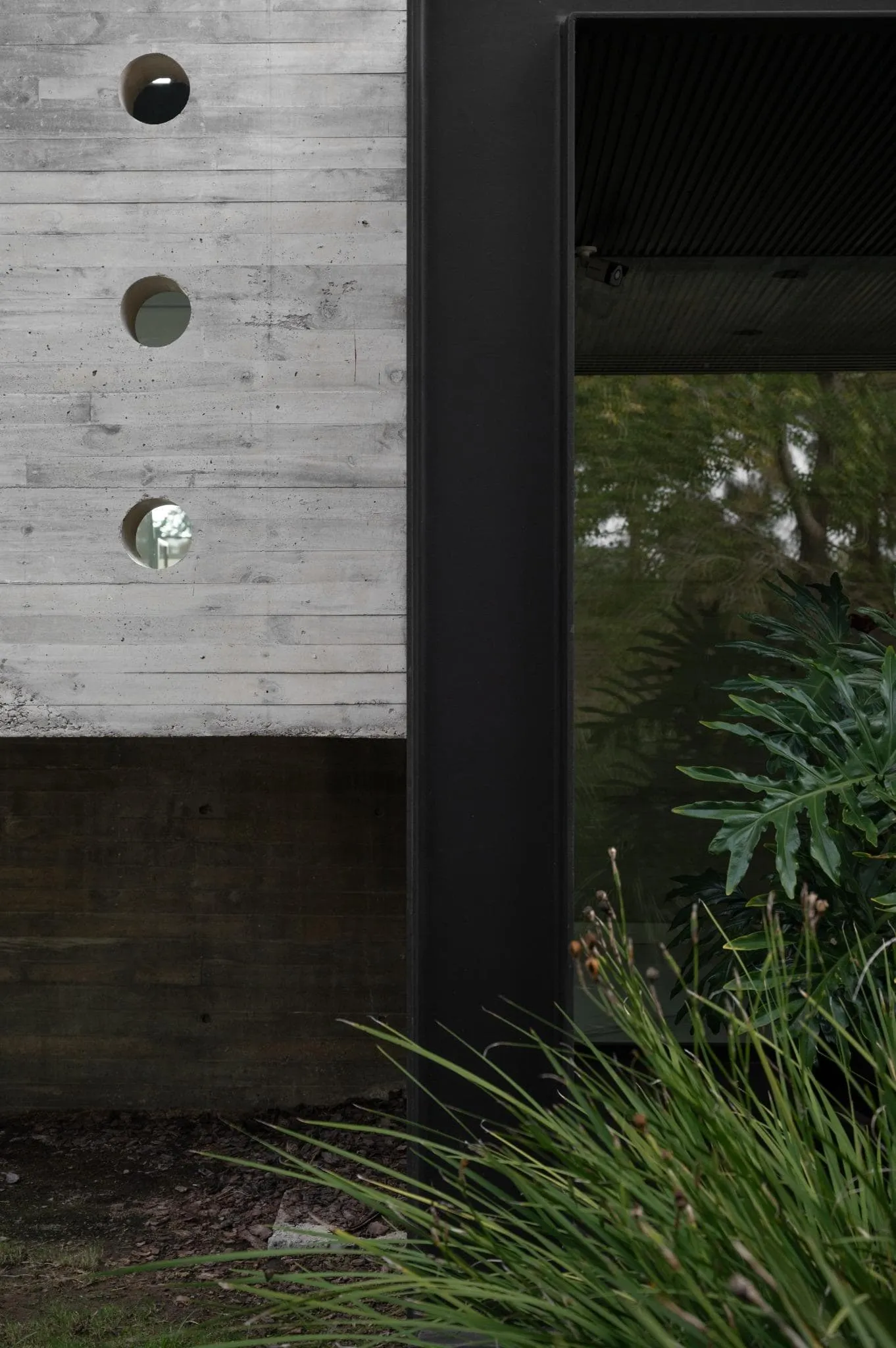 帕切科住宅入口穿孔混凝土墙与深色金属框架的交汇