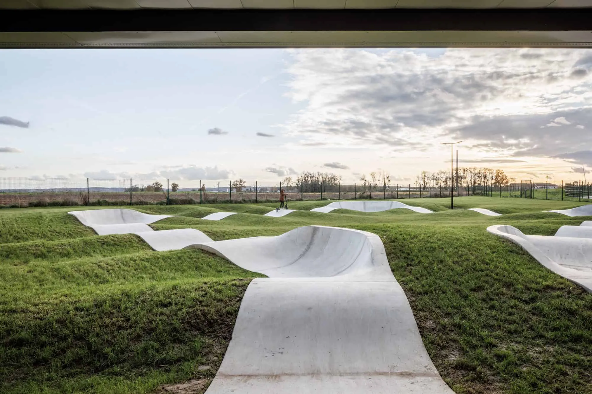 Wavy concrete skate park surrounding the main structure of the Mennese Sports Complex.