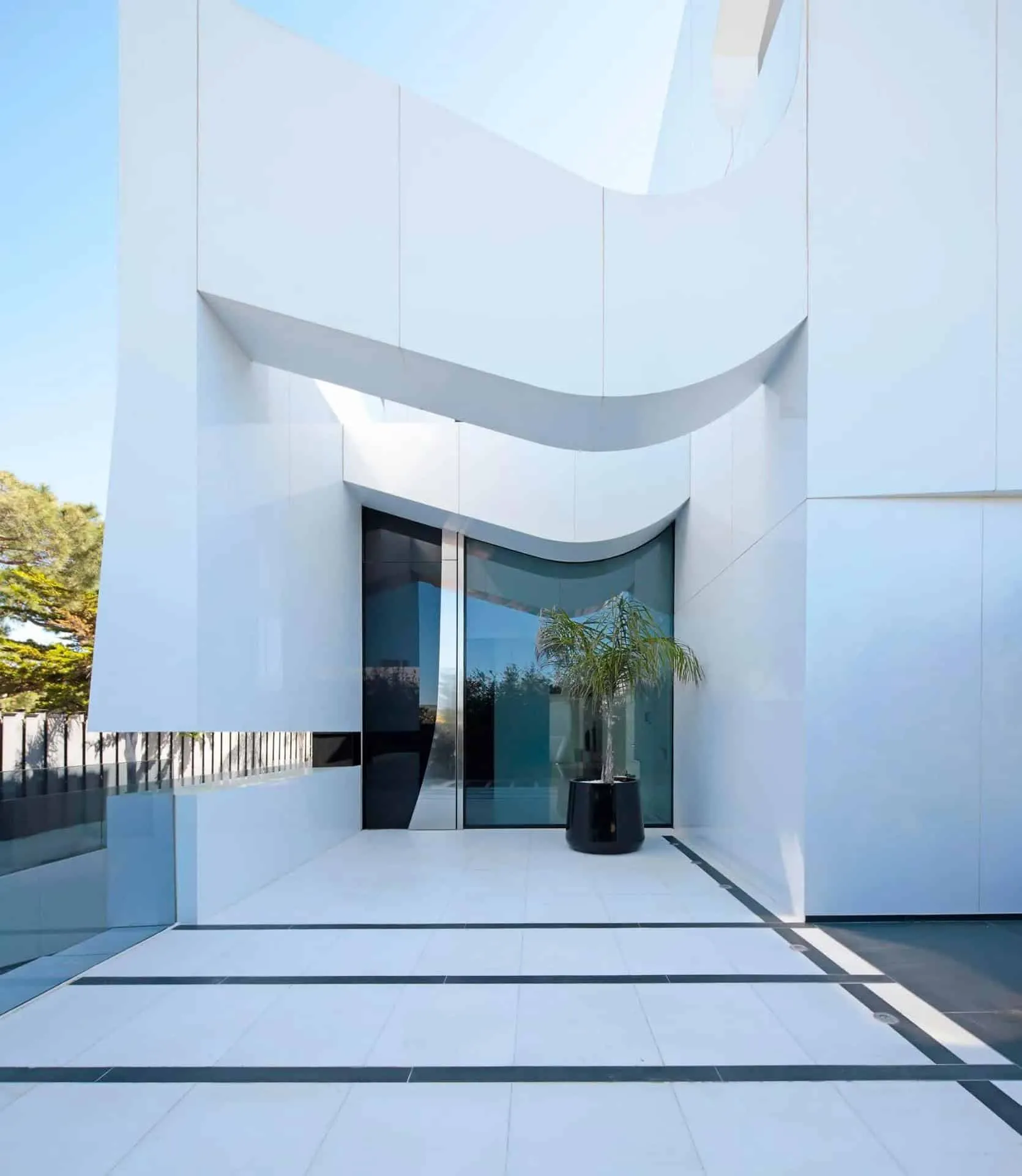 现代入口大厅，配有漂浮楼梯和自然光，展示瓜马尔别墅