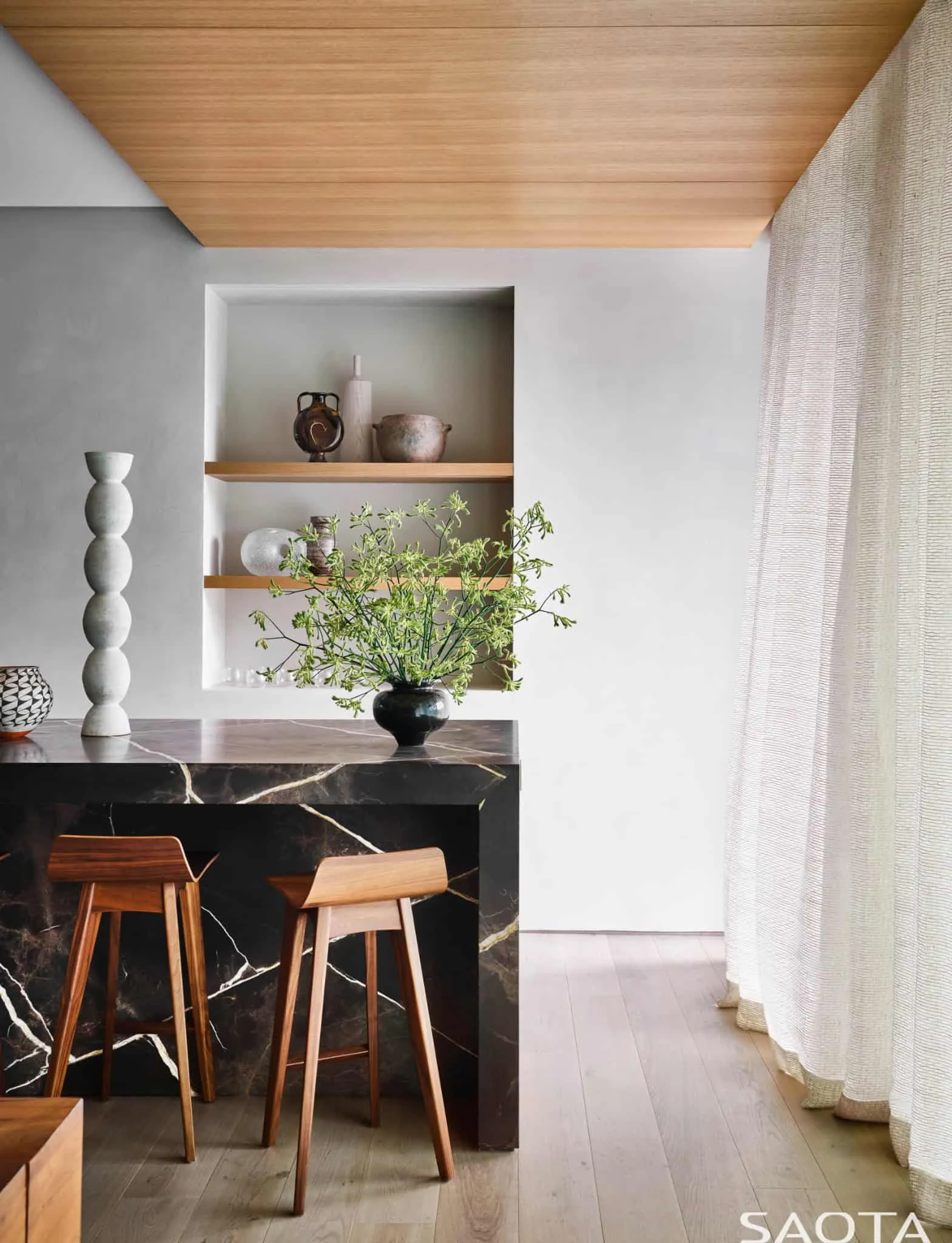 现代黑色大理石厨房台面，配有SAOTA设计的木质凳子