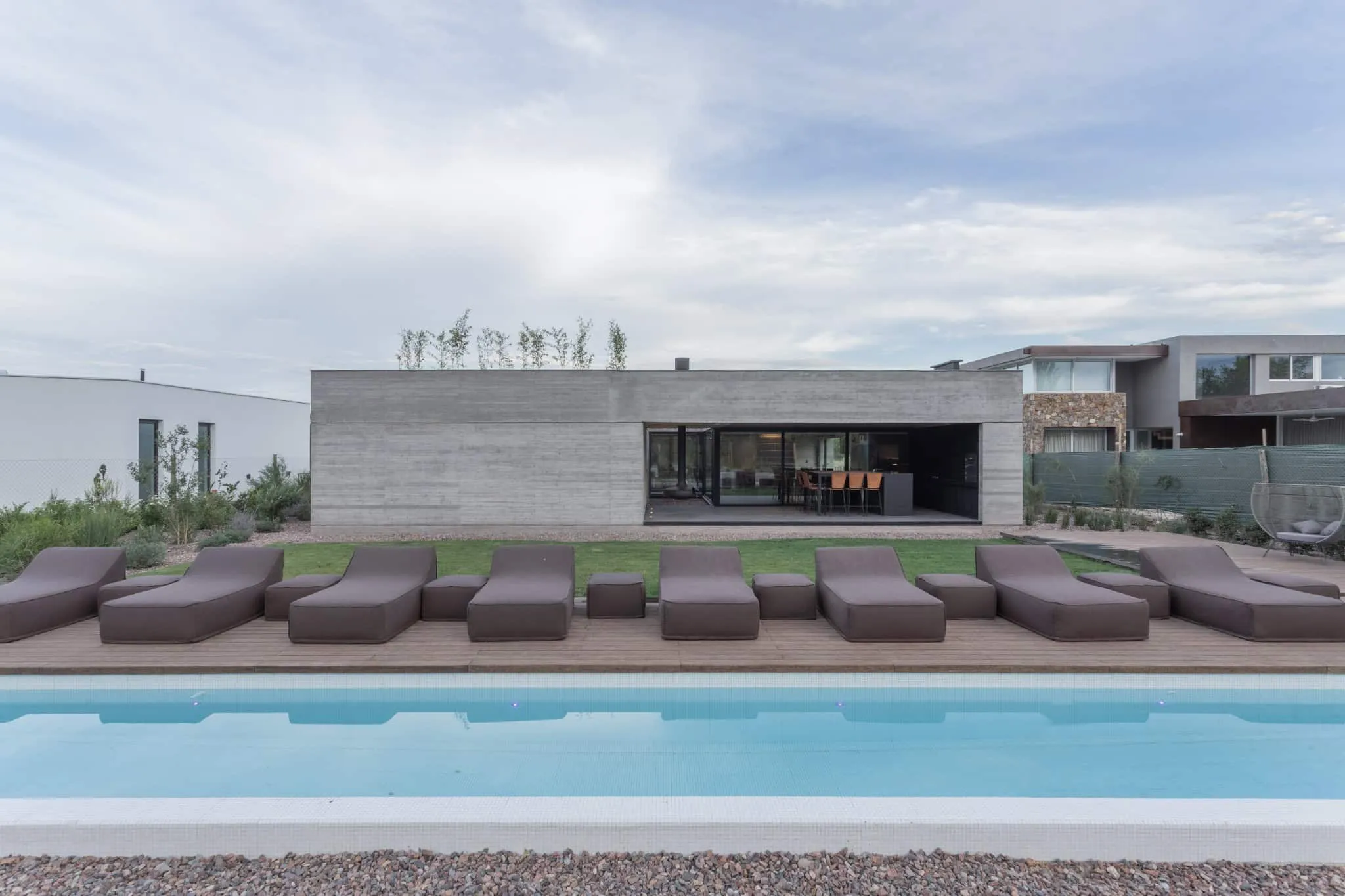 A4estudio设计的Casa Anabela阳光露台与泳池望向房屋。