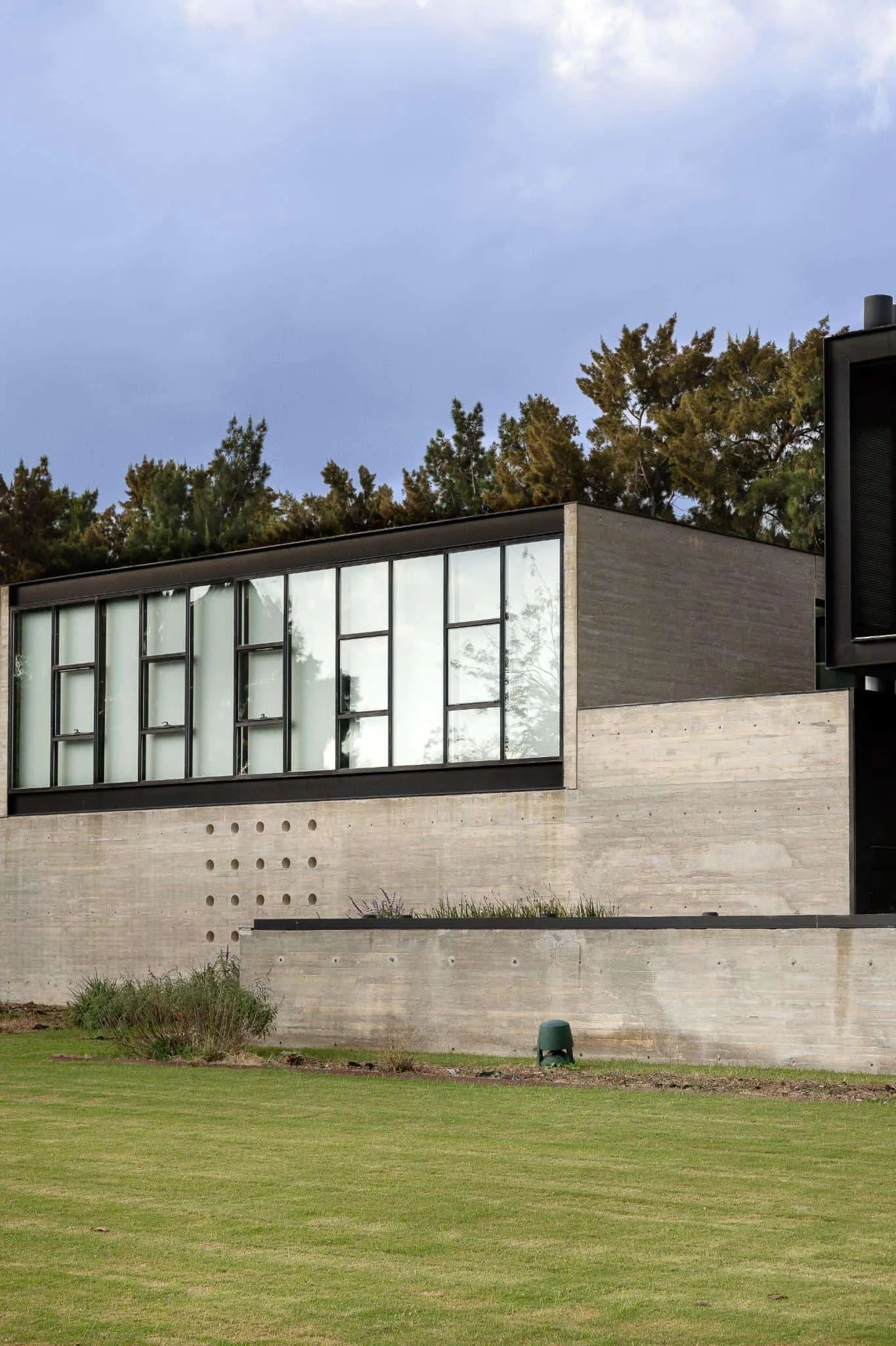 帕切科住宅私人翼侧视，从地板到天花板窗户与裸露混凝土