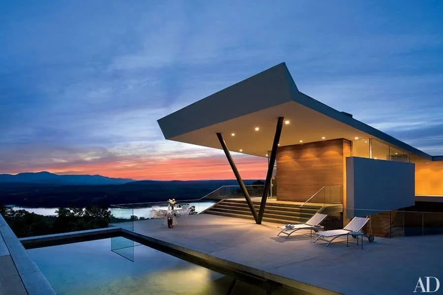 Modern house with a projecting structure, panoramic terrace and pool at sunset
