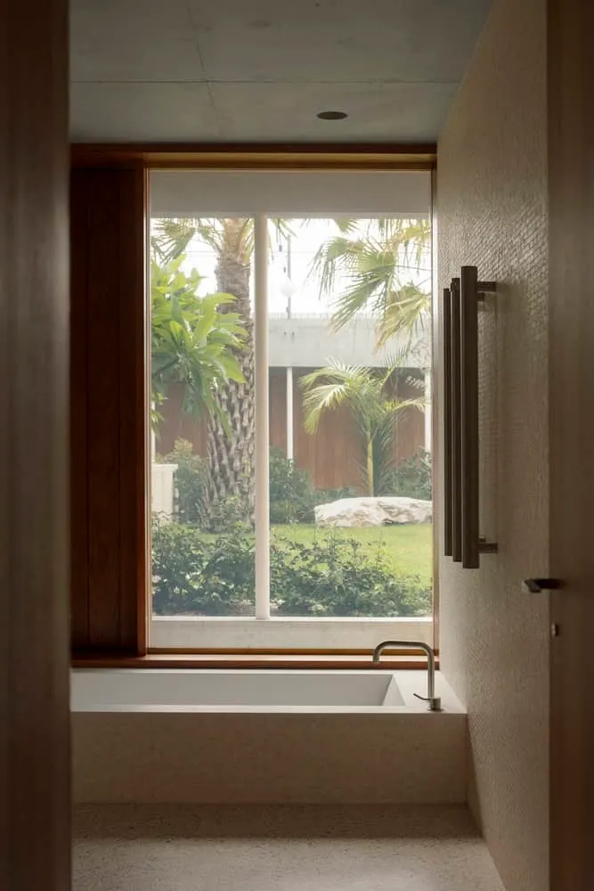 Tub next to large window overlooking lush tropical garden in Newcastle home