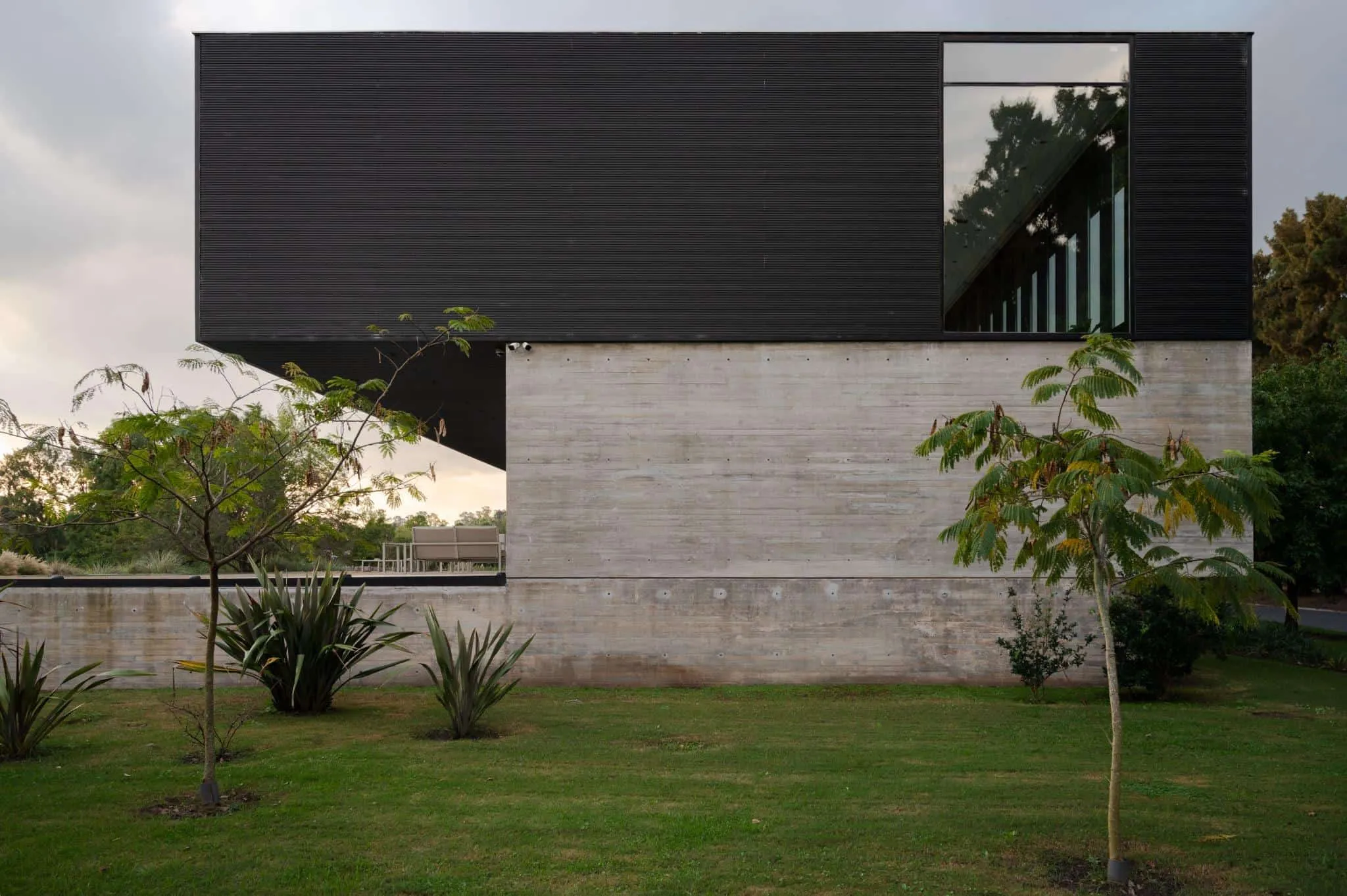 帕切科住宅侧面视角，混凝土与深色上部结构的鲜明对比