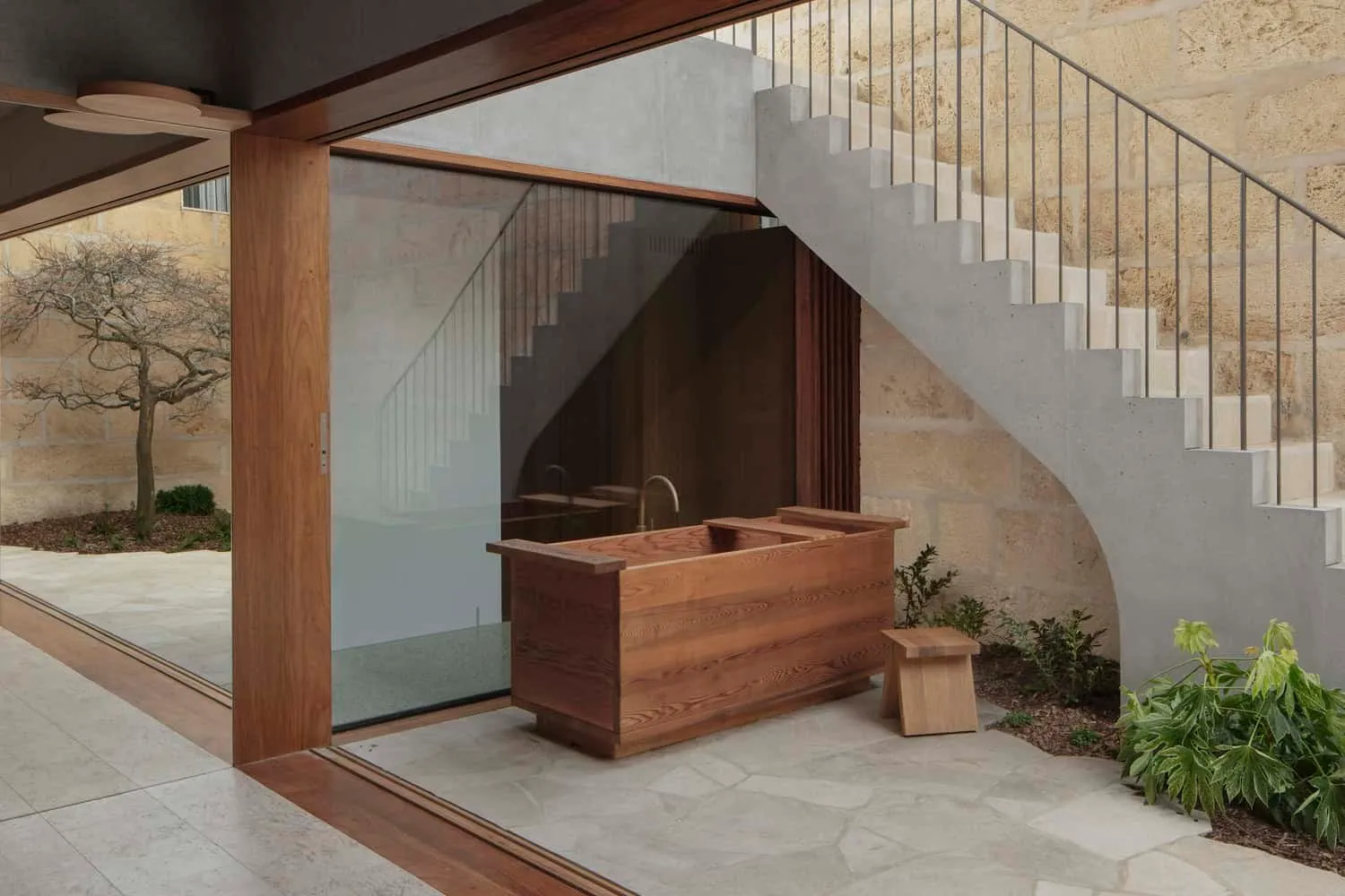 Concrete stairs above handcrafted wooden tub in courtyard of Newcastle home