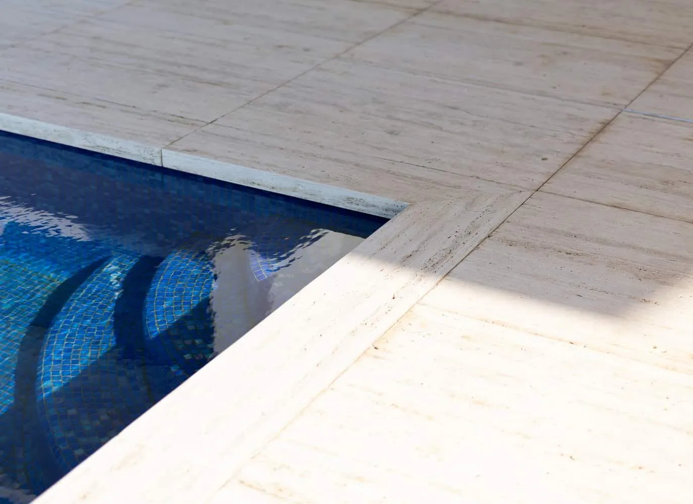 Detail of steps with natural marble and deep blue pool tiles