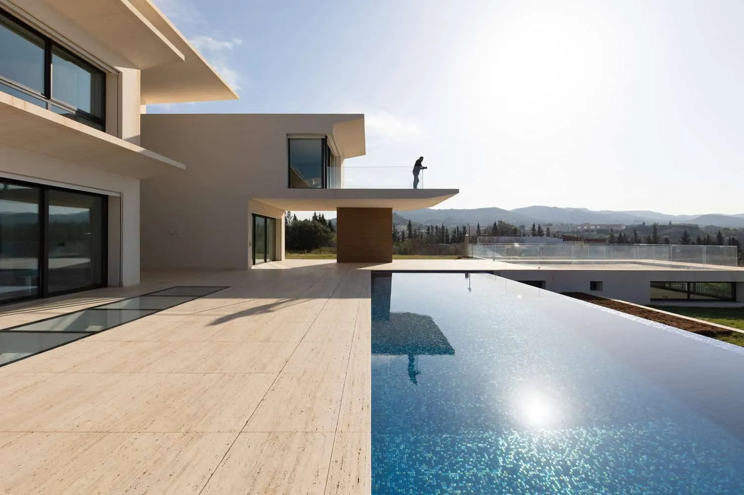 Infinity pool at sunset reflecting the sky and architecture of the house