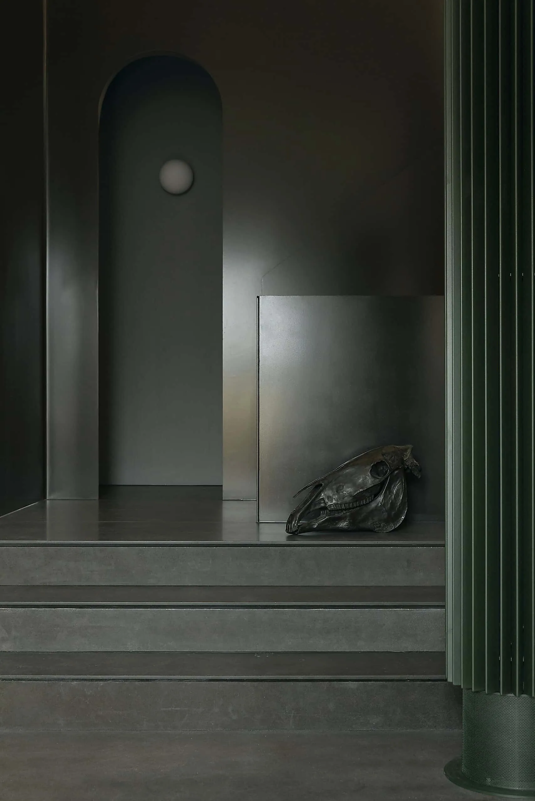 Modern minimalist interior with dark color palette and artistic sculpture, showcasing elements of contemporary architectural design.