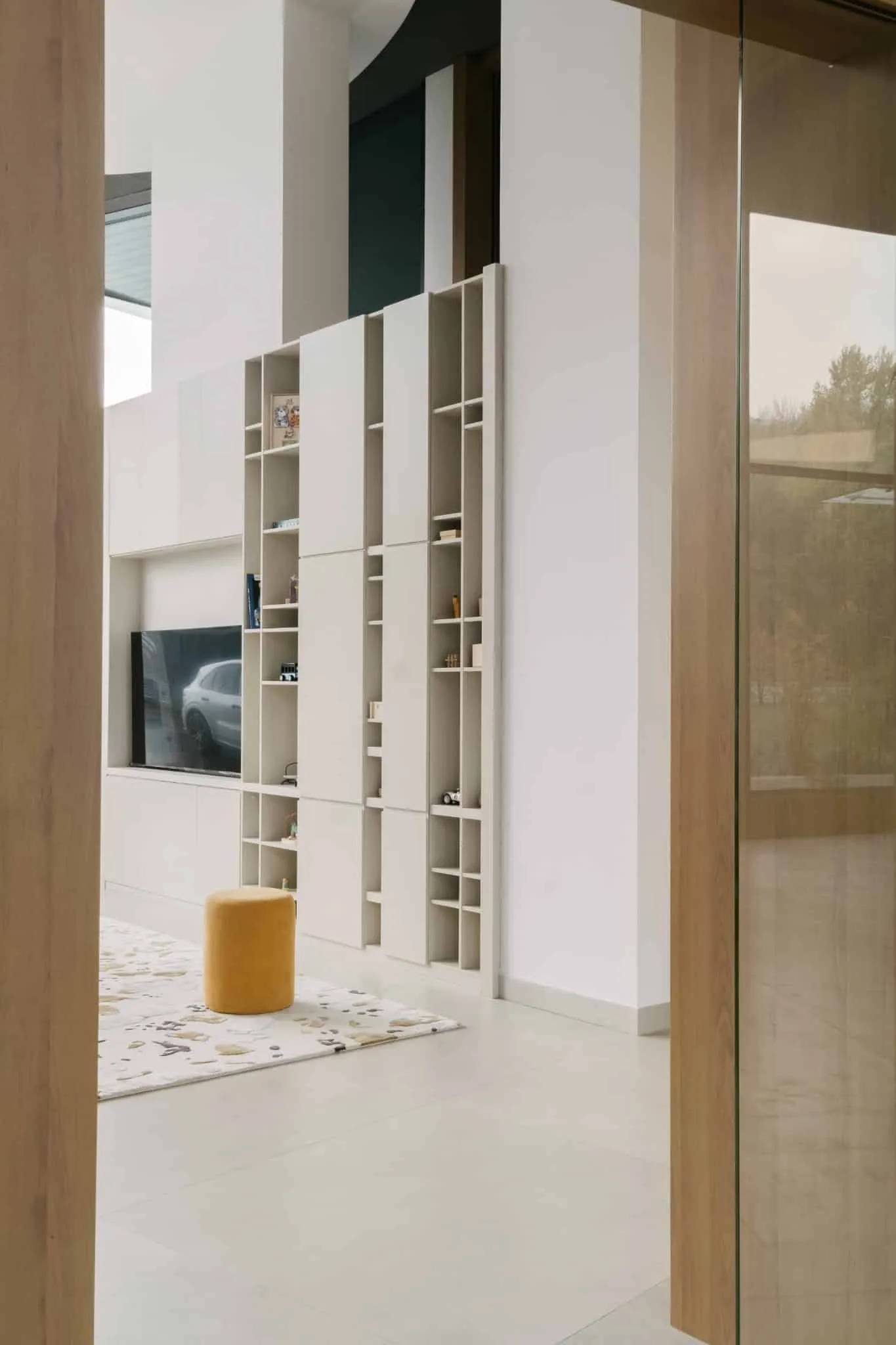 Modern interior with custom white modular shelf with open cell and integrated TV, minimalism, clean lines and natural lighting for modern home design.