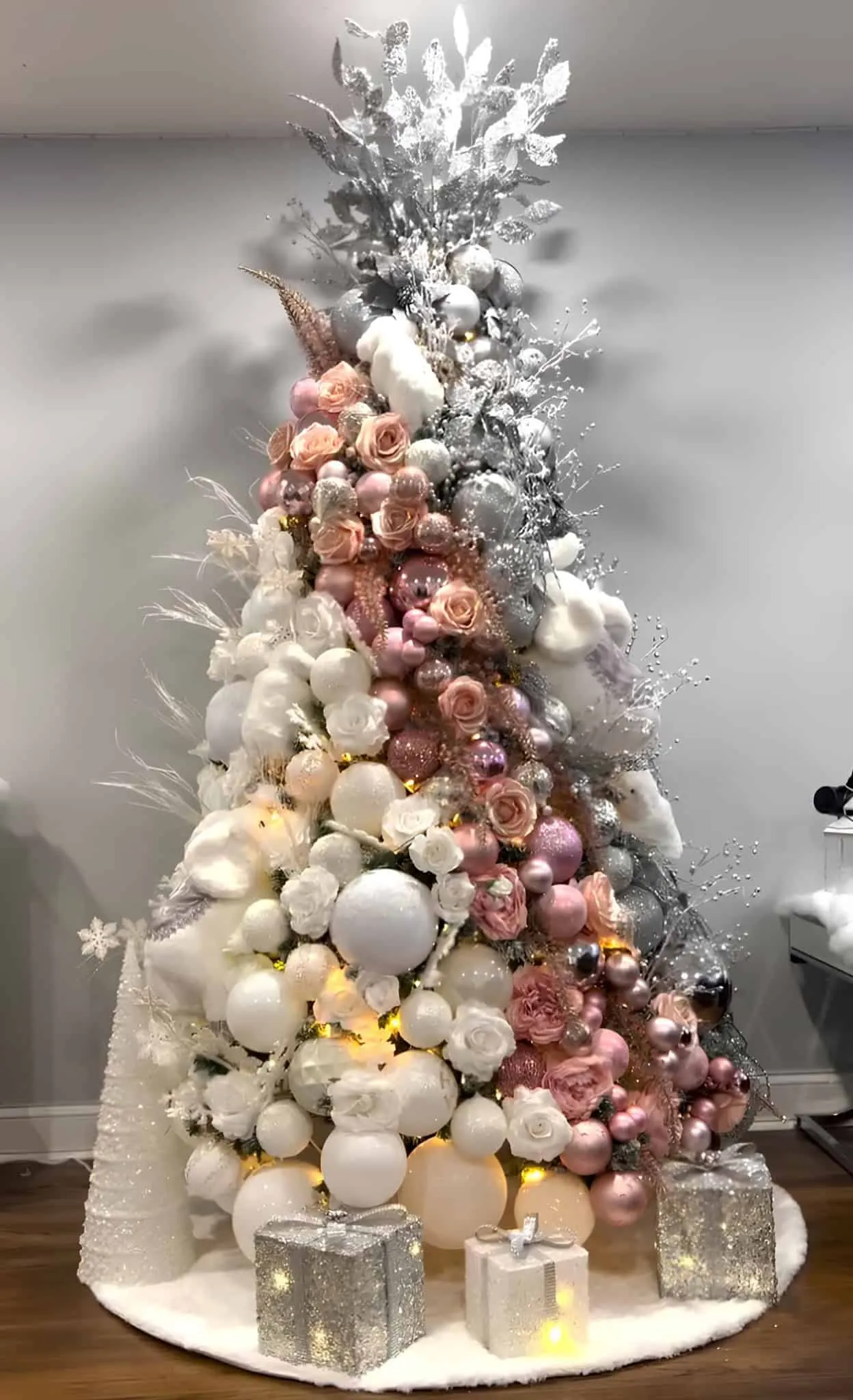 粉红银圣诞树，装饰着玫瑰、珍珠点缀和闪亮礼物