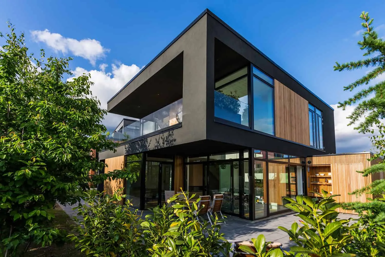 Villa S — dark wooden cladding with deep window sills and metallic accents