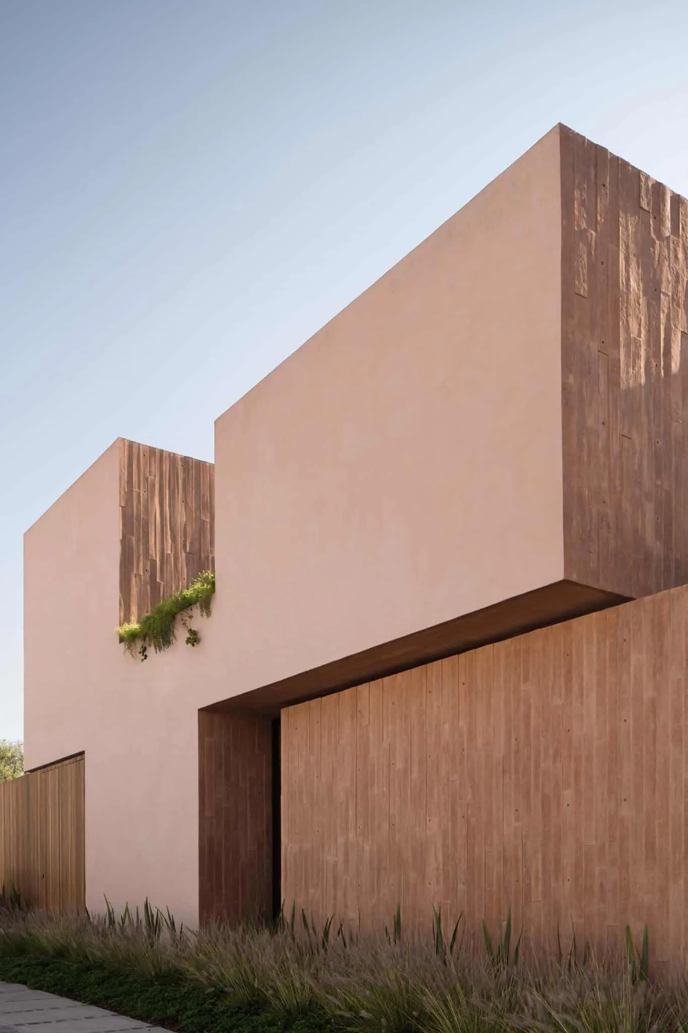 卢哈米博住宅立面细节，由Jorge Garibay Arquitectos设计——多层粉色抹灰与木质纹理在墨西哥胡里基拉