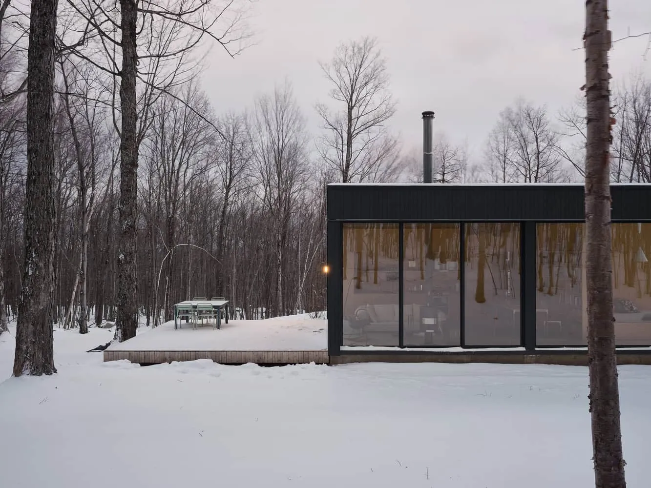 Maison Spiron — terrasse hivernale et façade avec grandes fenêtres à Potton, Québec, Canada