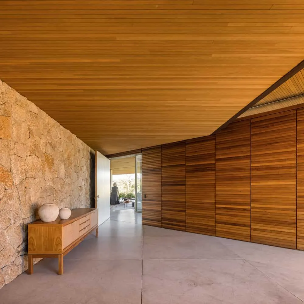 House TM by Jacobsen Arquitetura – hall with stone wall and cabinet, Brazil