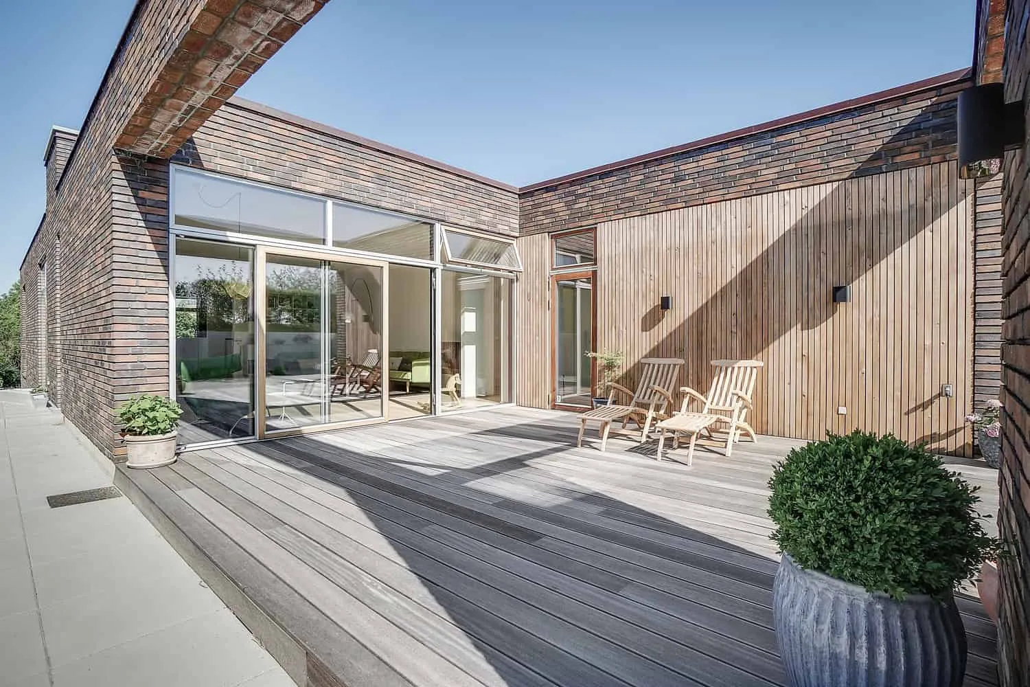 Composed perspective of the villa settling into the sloped site at dusk