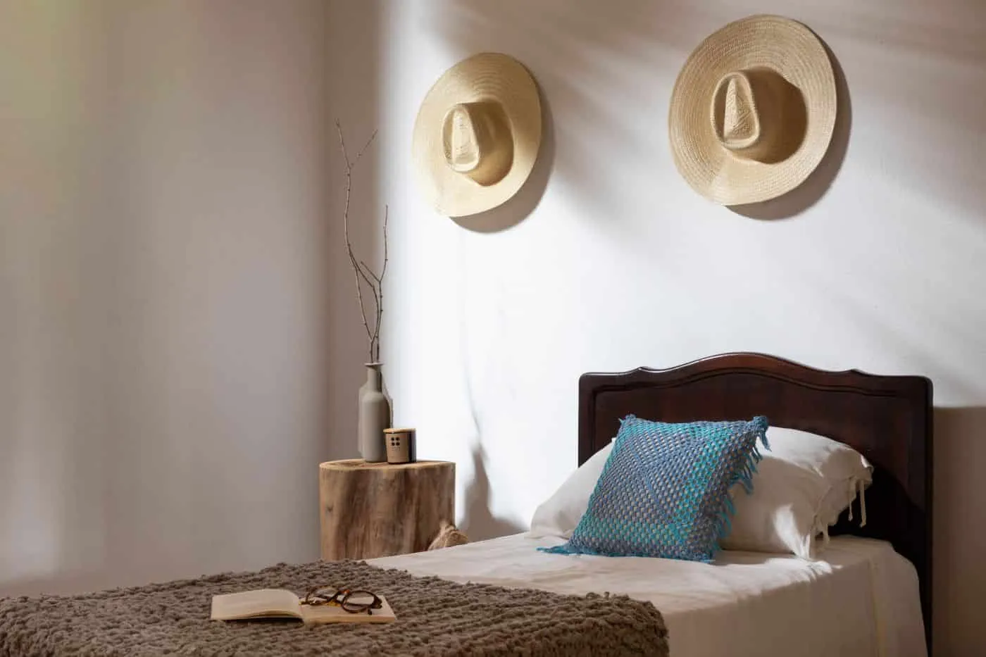 Refúgio Rural — guest bedroom with vintage family bed, straw hat and logo on nightstand in Itajobi, São Paulo