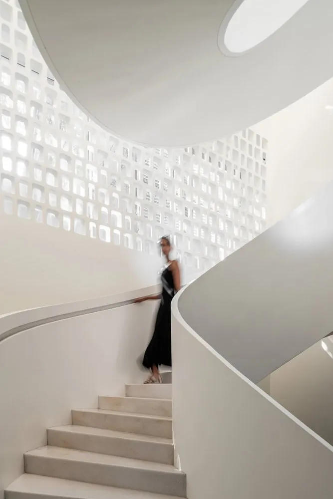 Close-up of perforated staircase screen and curved staircase in House NINE X NINE