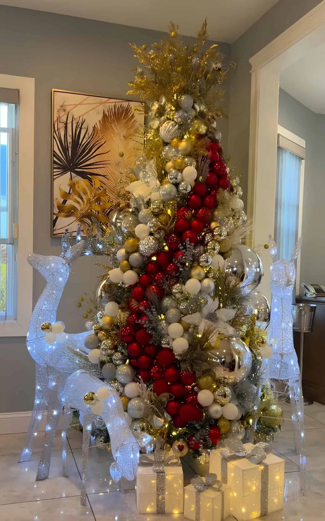 金、银和白圣诞树，装饰着明亮红色瀑布丝带和照亮的驯鹿