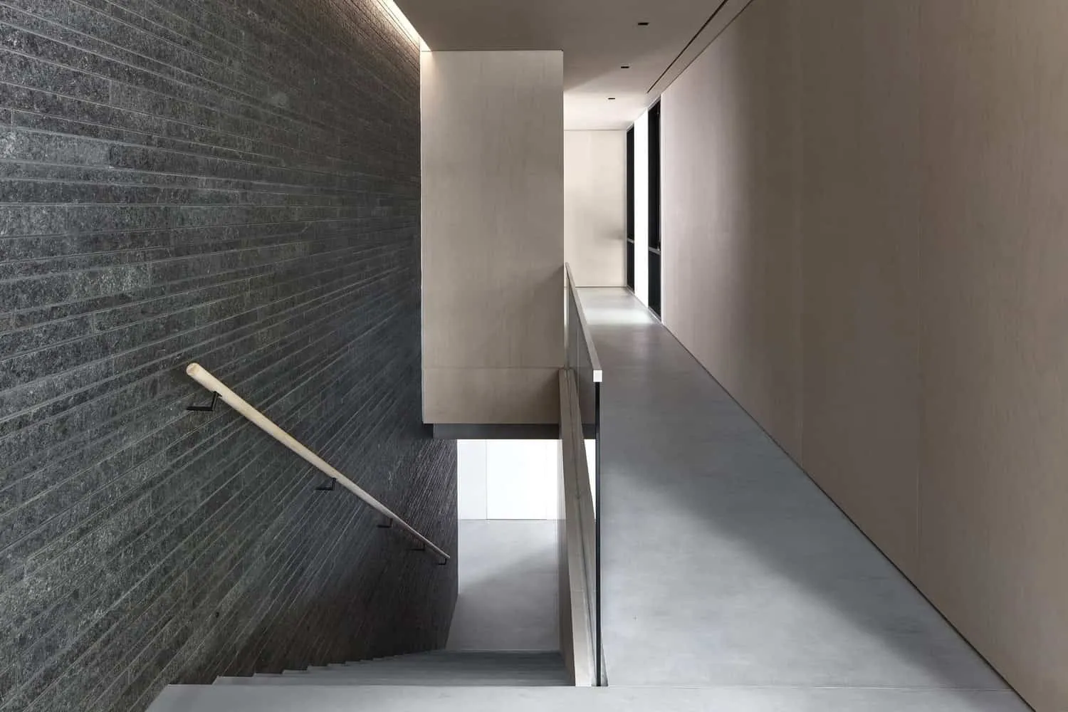 Elegant Modern Corridor with Minimalist Design, Concrete Floor, Textured Dark Wall and Large Windows for Natural Light