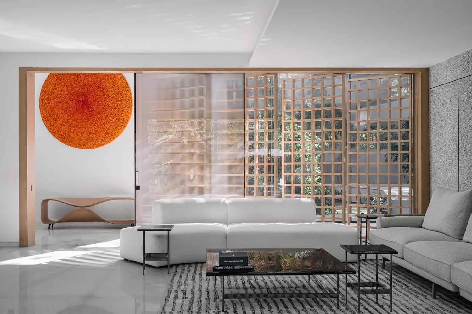Living room with orange circular artwork and wooden screen in House NINE X NINE in Gandhinagar