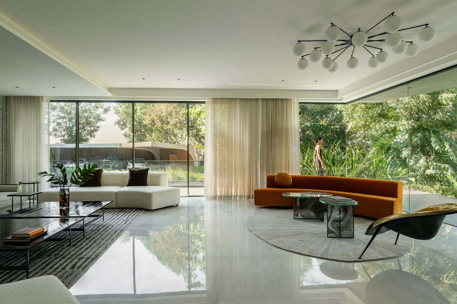 Living room with panoramic glazing, framing garden views in House NINE X NINE in Gandhinagar