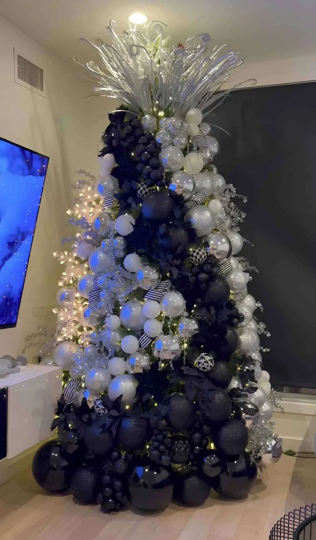 黑、白、银圣诞树，装饰着现代饰品和金属枝条